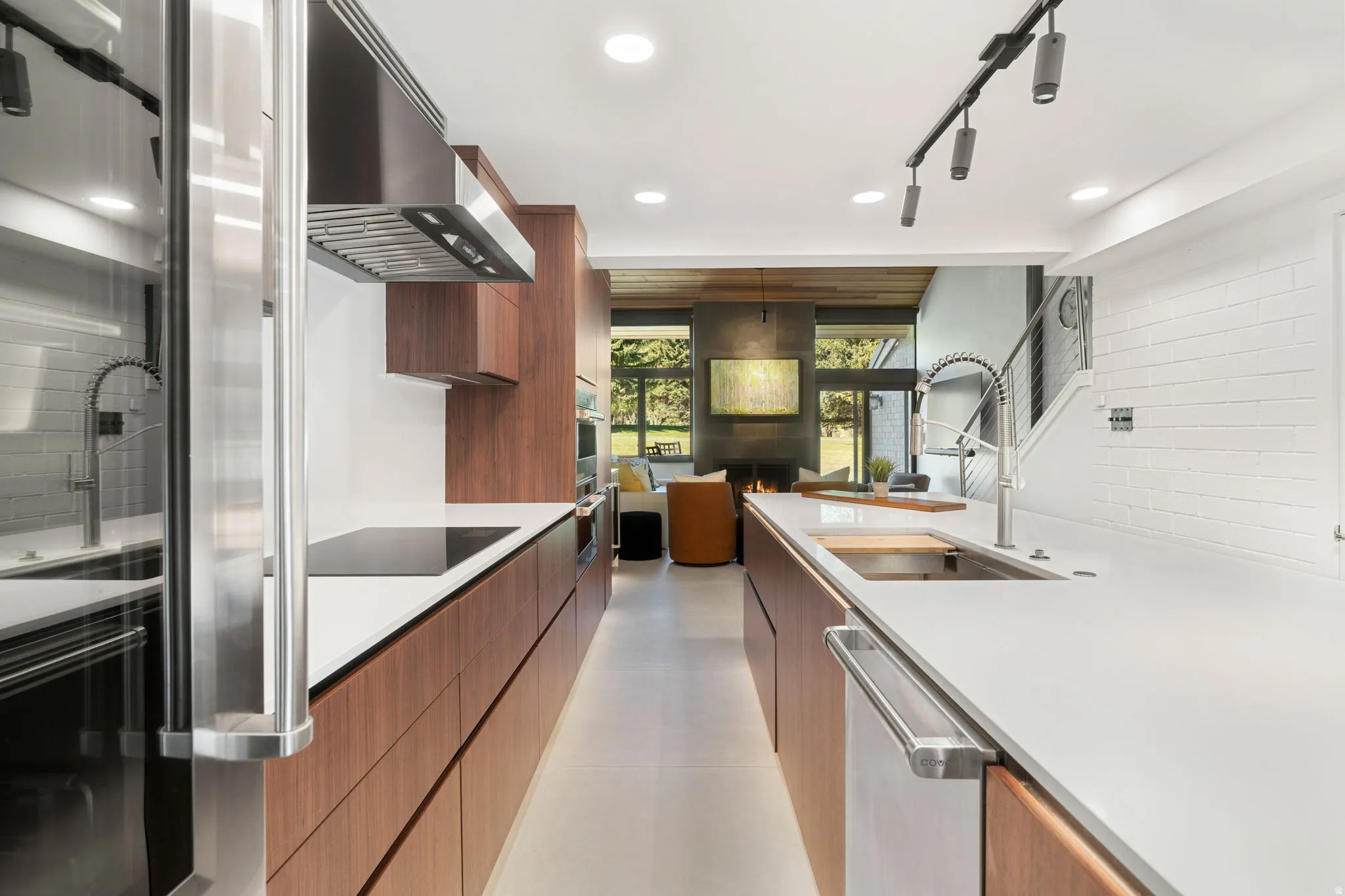 Contemporary kitchen featuring white countertops, stainless steel appliances, and integrated wood-finish cabinetry