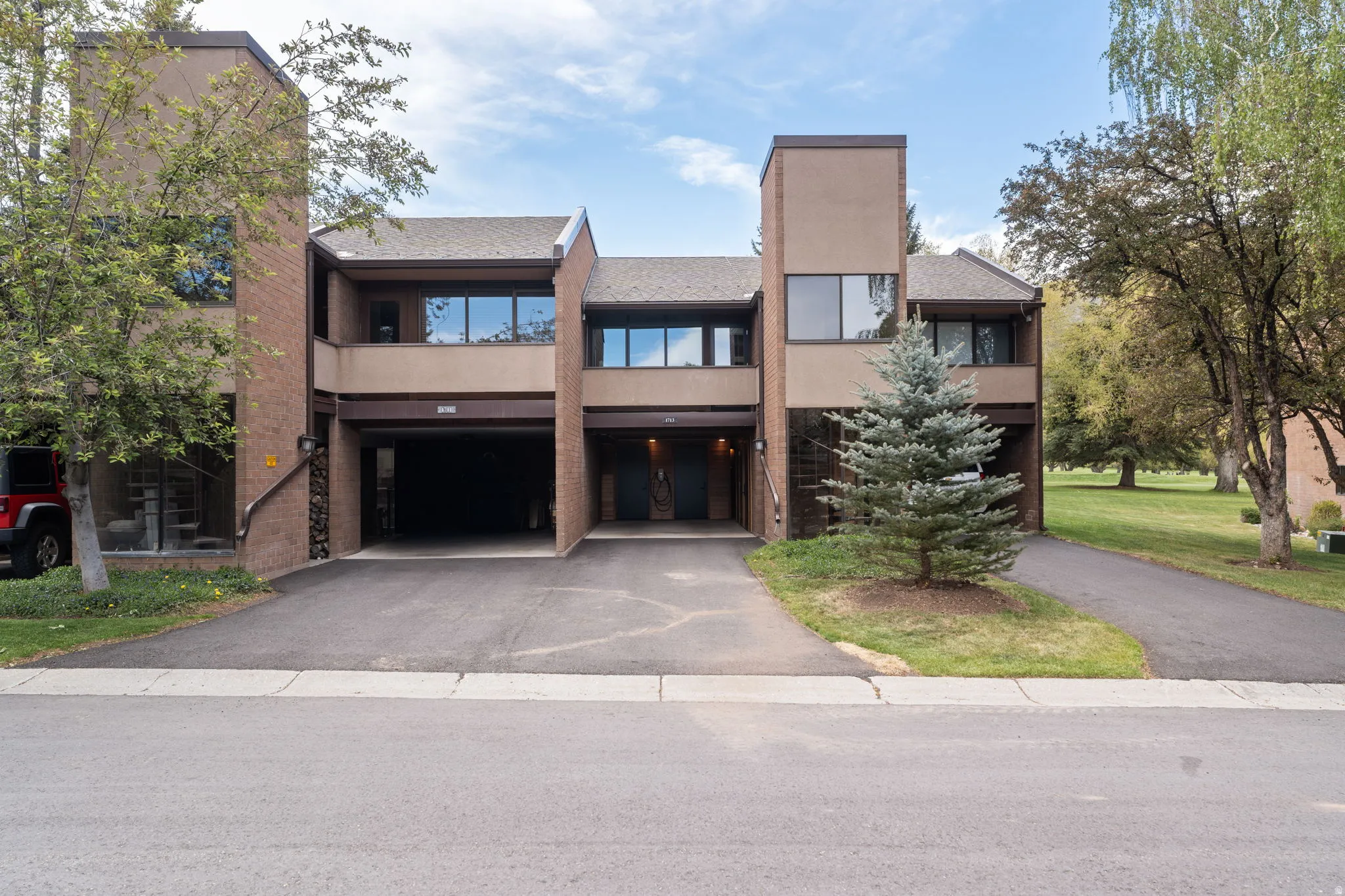 Multi-story property featuring a brick and stucco exterior, prominent windows, and covered parking bays