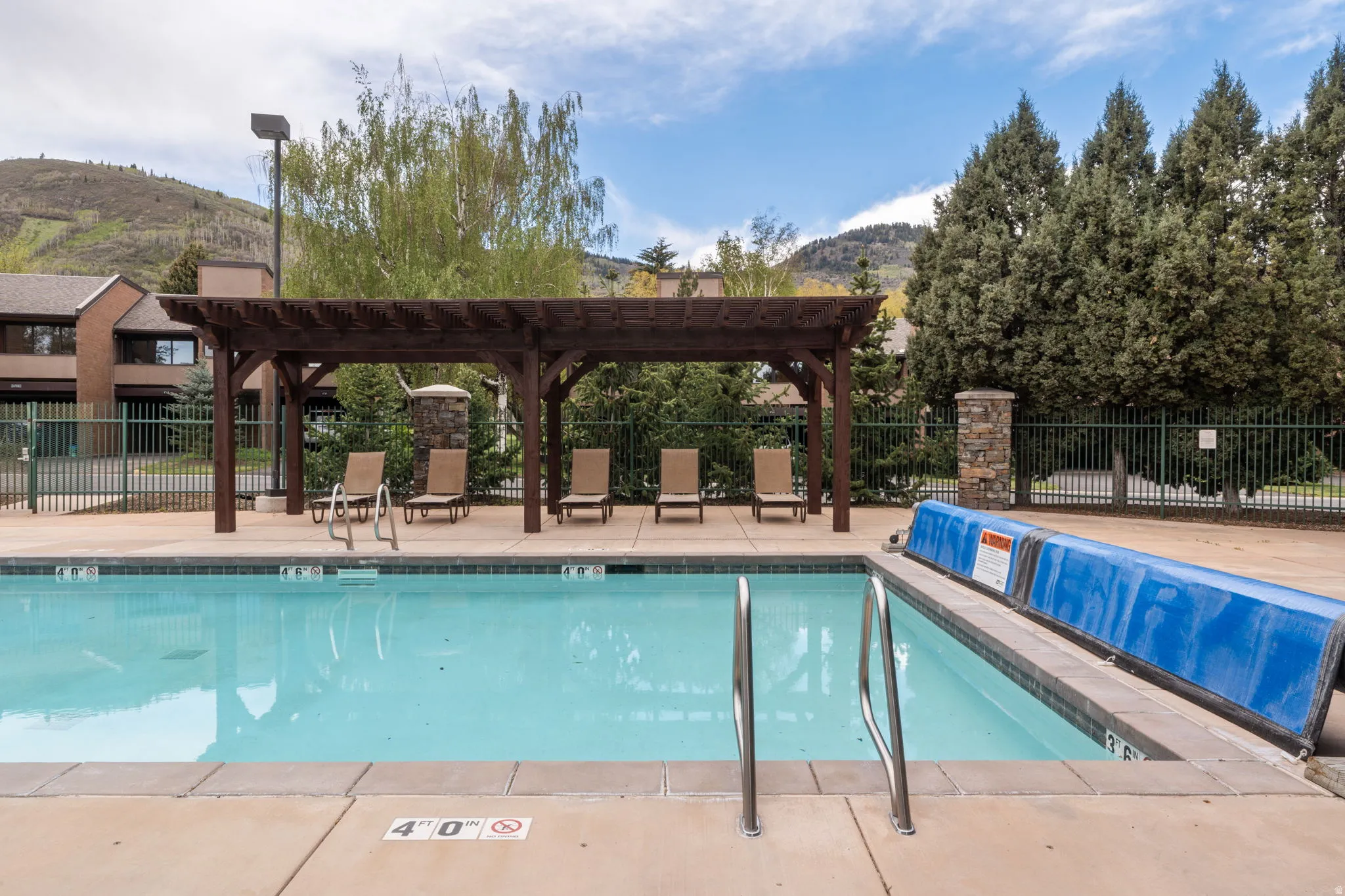Outdoor pool area featuring a concrete deck and a wooden pergola structure