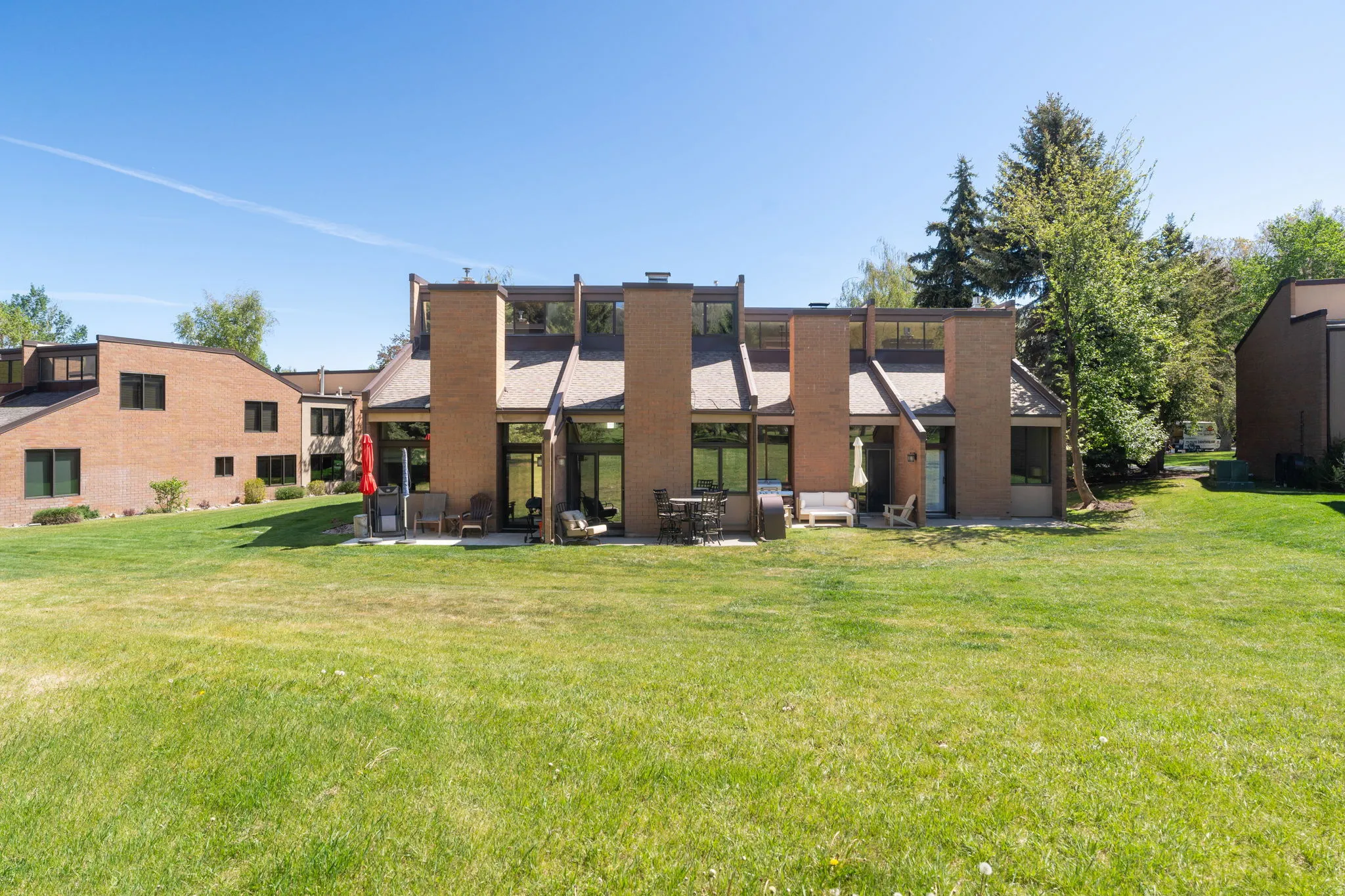 Expansive green space backing to a brick exterior with multiple patios