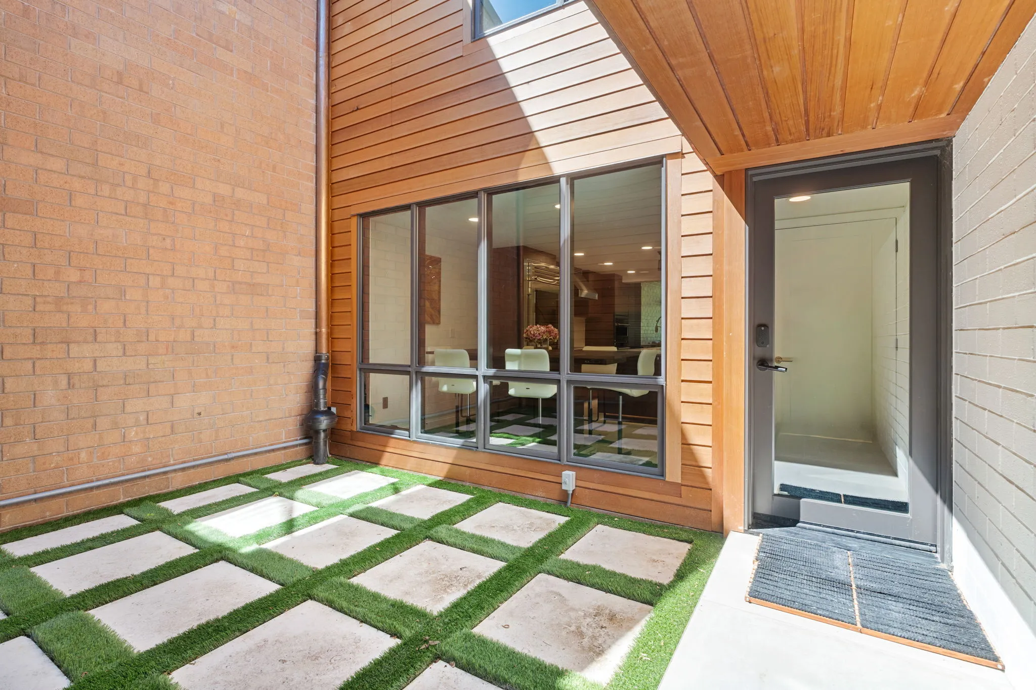 Outdoor patio featuring concrete pavers interspersed with artificial turf