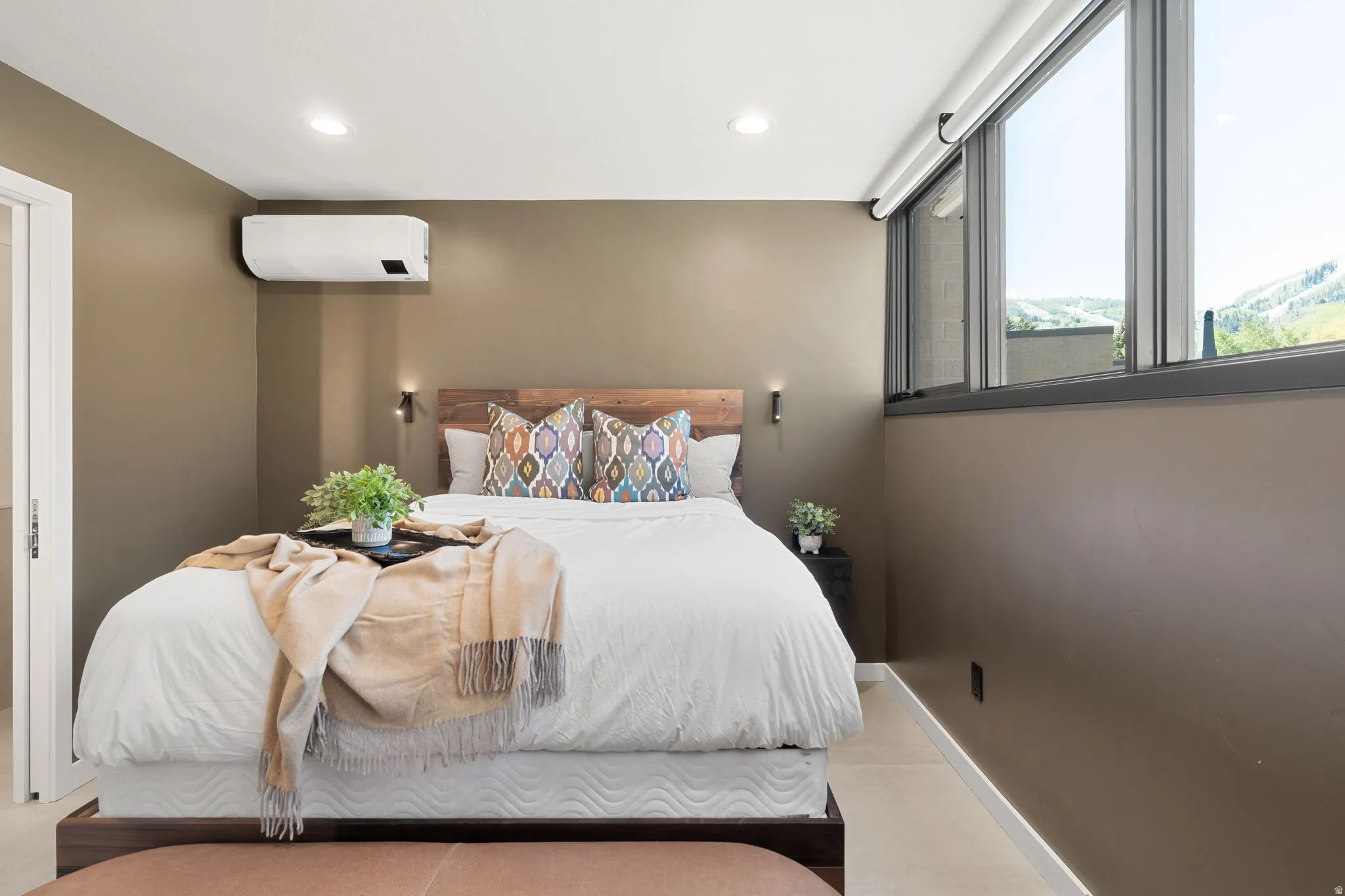 Bedroom featuring a wood-finish headboard, wall-mounted sconces, and recessed lighting