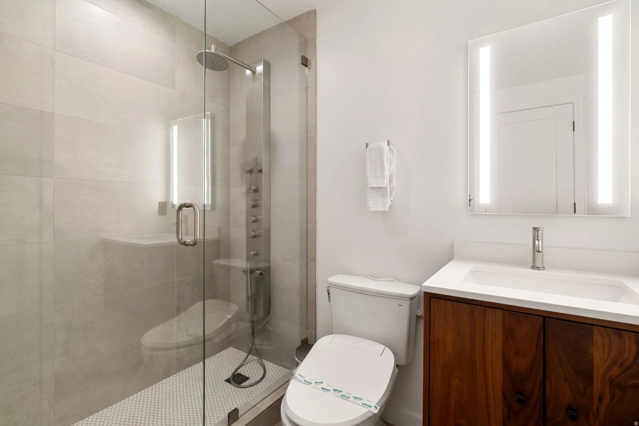 Contemporary bathroom featuring a glass-enclosed shower with a rainfall showerhead and a multi-jet panel