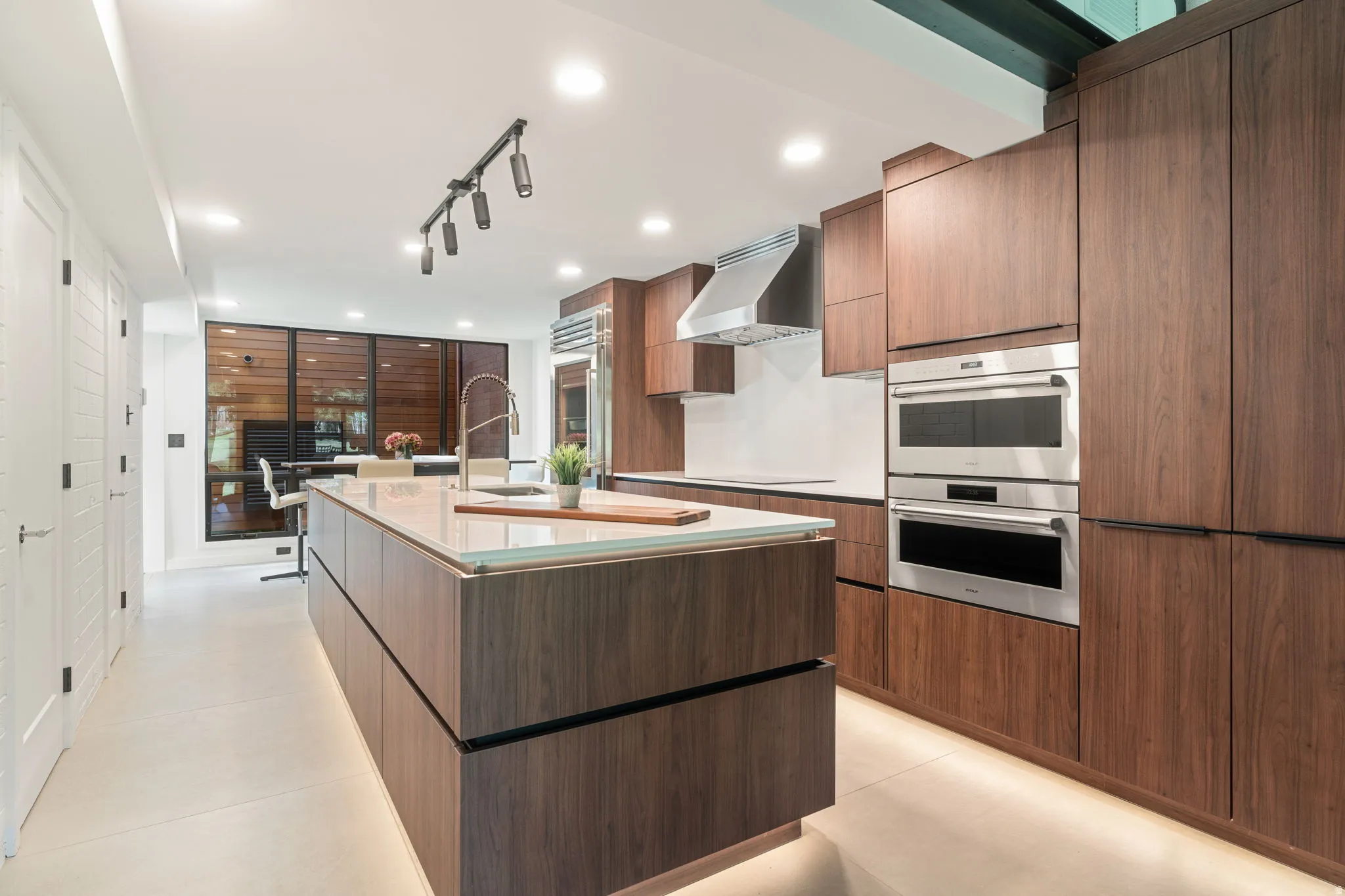 Modern kitchen featuring warm wood-finish cabinetry and a large central island with an undermount sink and contemporary faucet