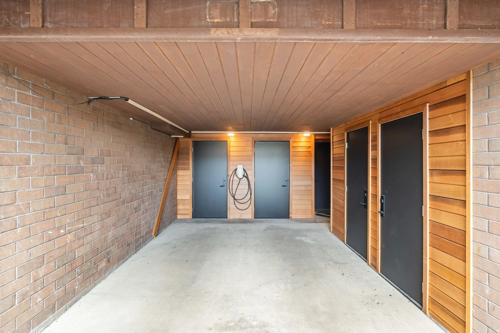 Covered parking area featuring a brick wall and a wood-finish ceiling