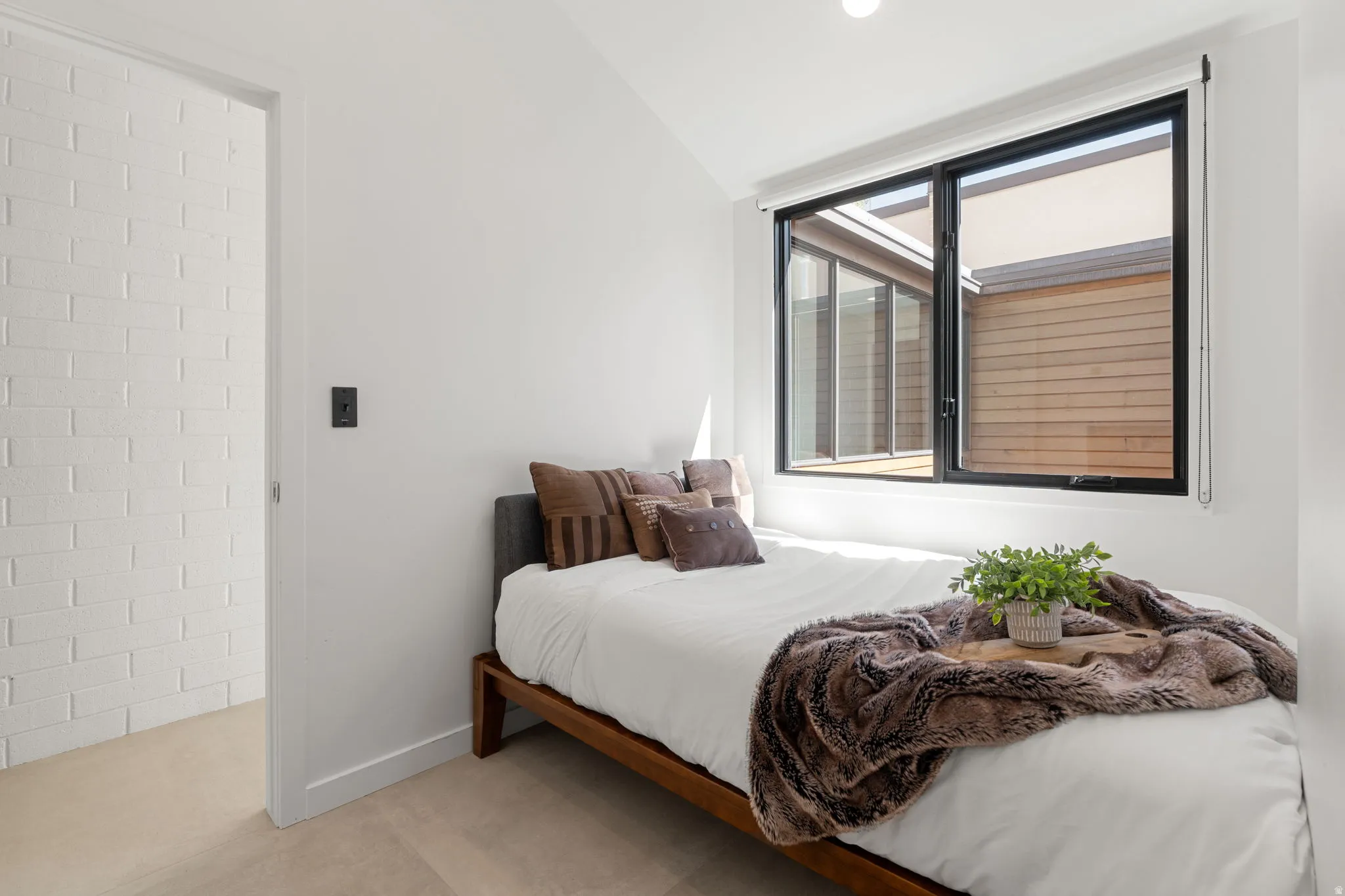 Bedroom featuring a large black-framed window, white walls, and light-colored carpeting