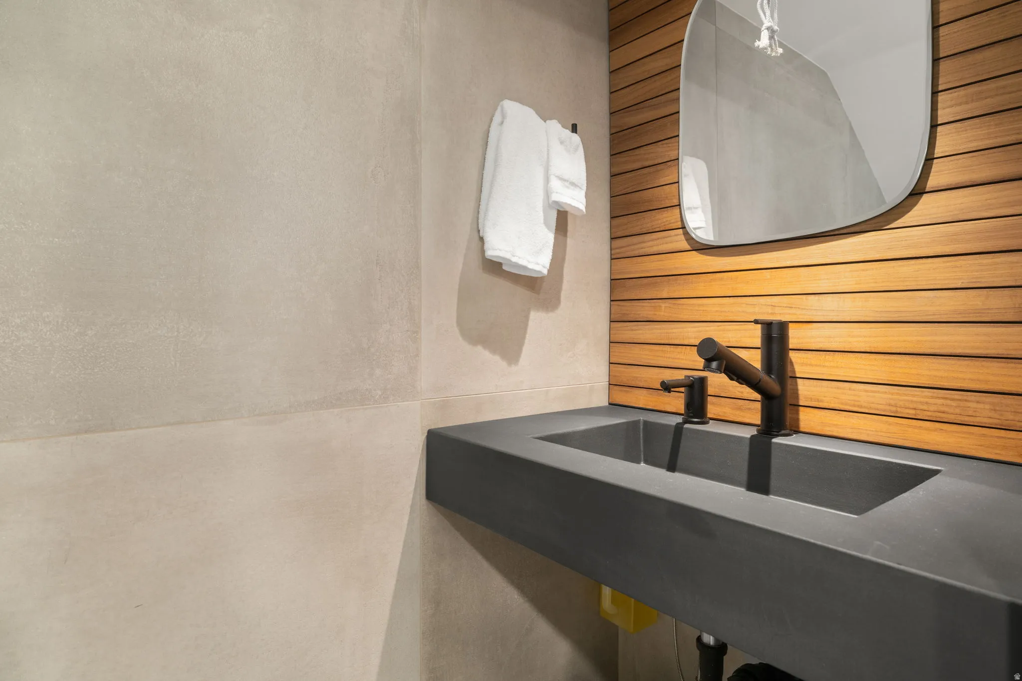 Floating dark gray countertop with integrated rectangular basin, featuring a matte black faucet and soap dispenser