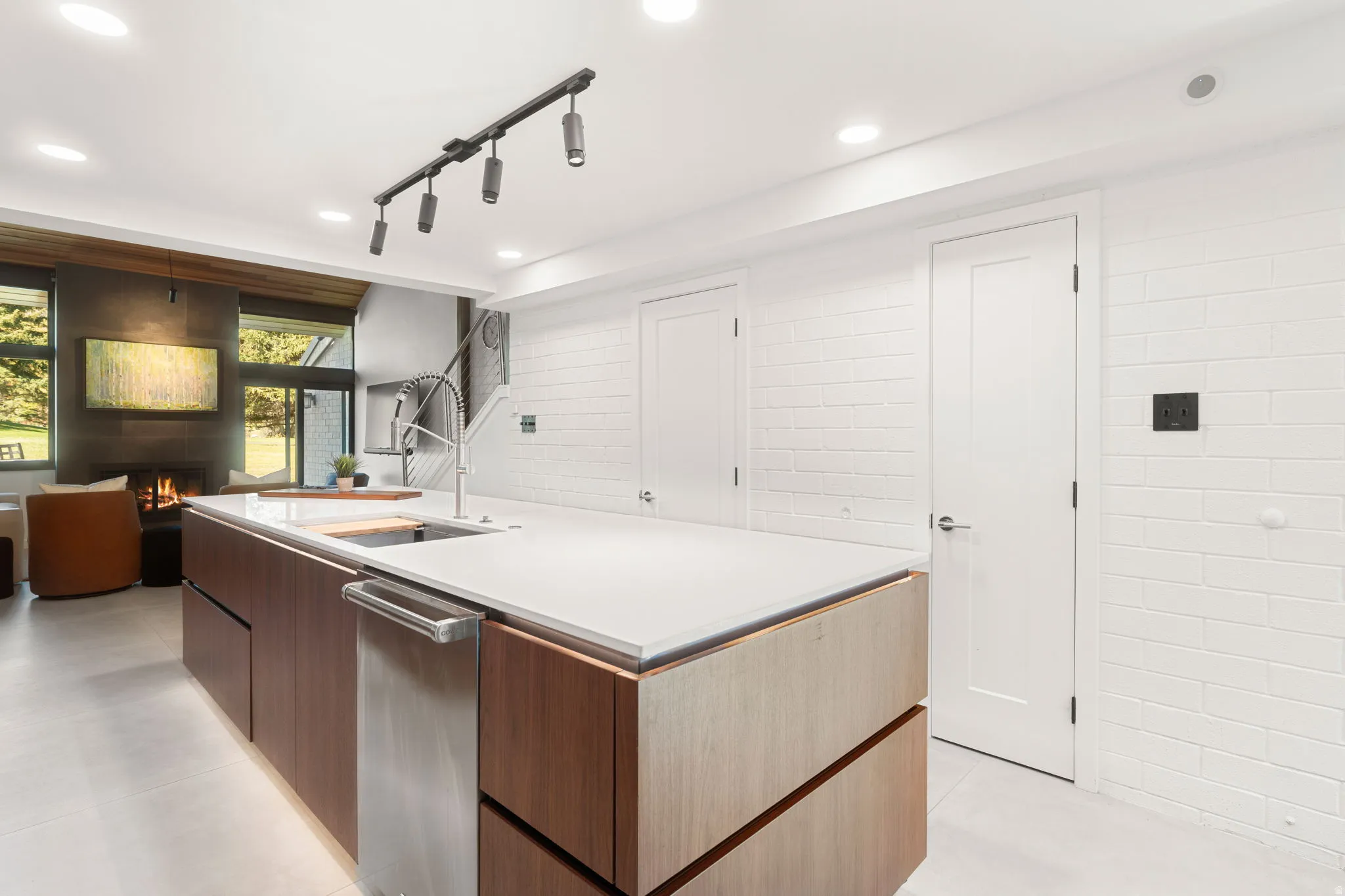 Kitchen island with integrated stainless steel dishwasher, white countertop, and wood-finish cabinetry