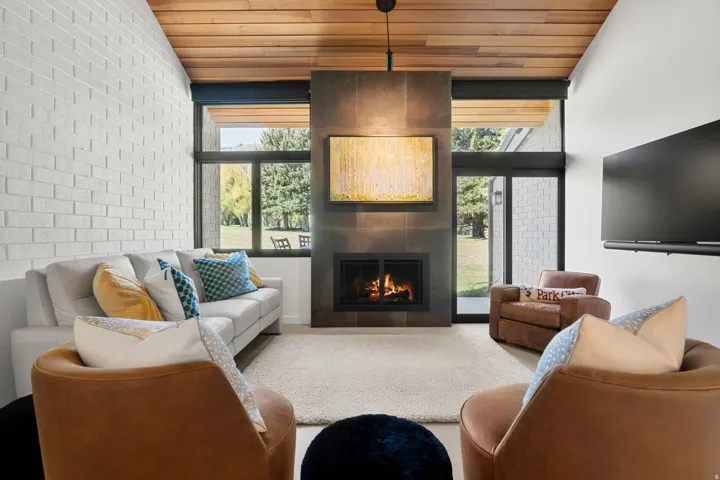 Living area featuring a floor-to-ceiling fireplace with a dark tile surround and a wood-slat ceiling