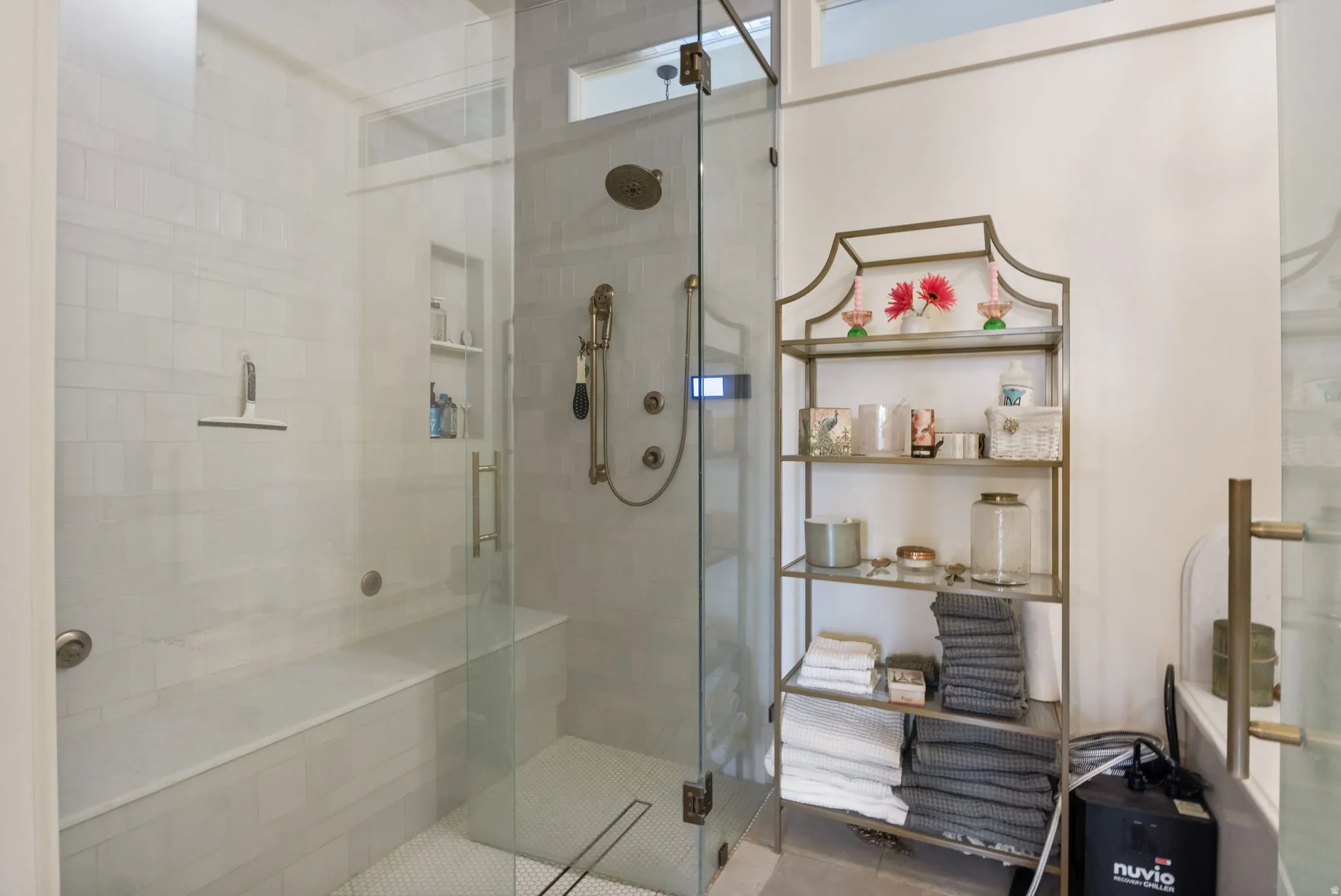 Walk-in shower featuring a glass enclosure, built-in bench, recessed shelf, and multiple shower heads