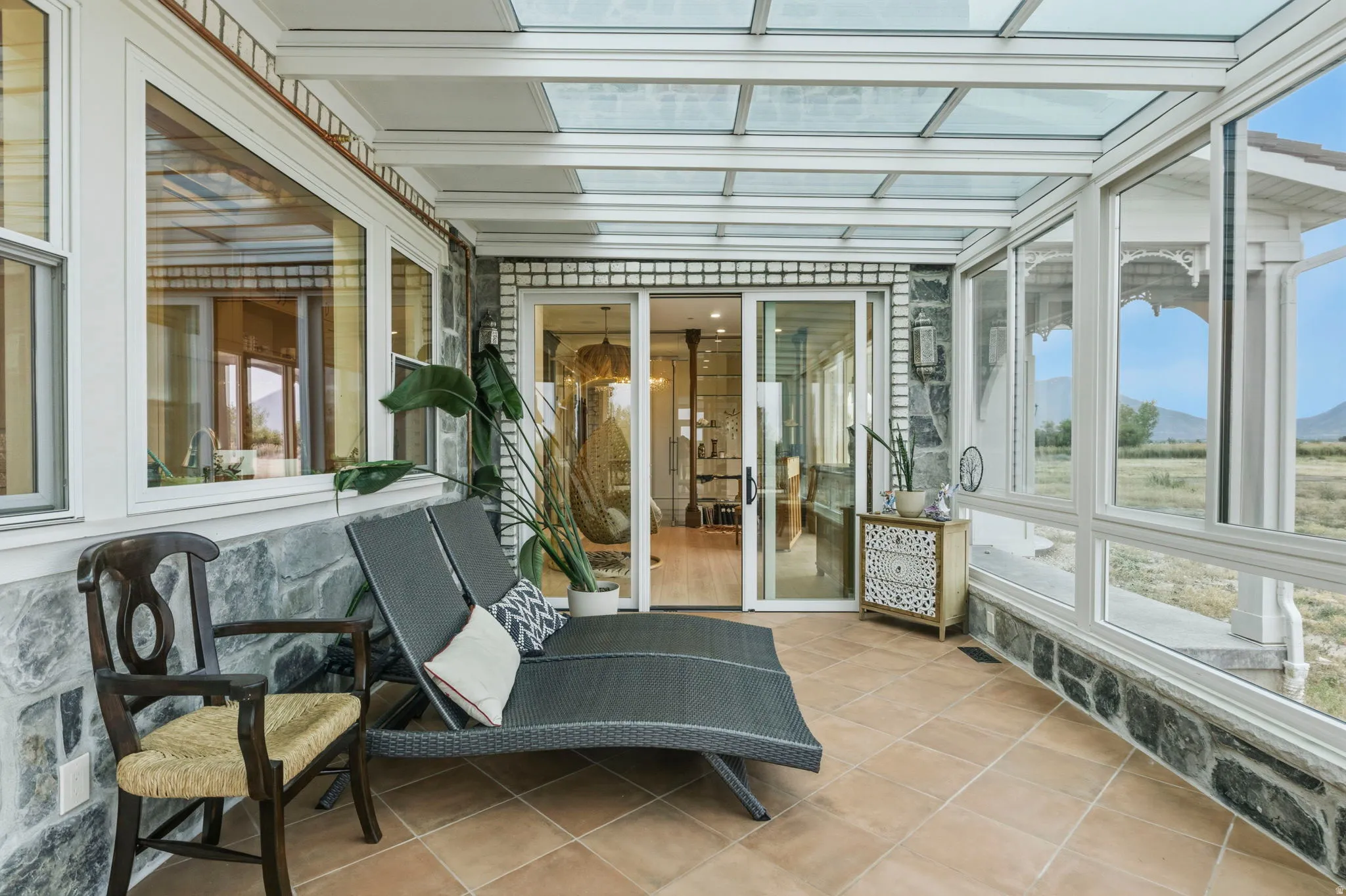 Sunroom featuring a glass panel ceiling, full-height windows, tiled flooring, and a stone accent wall