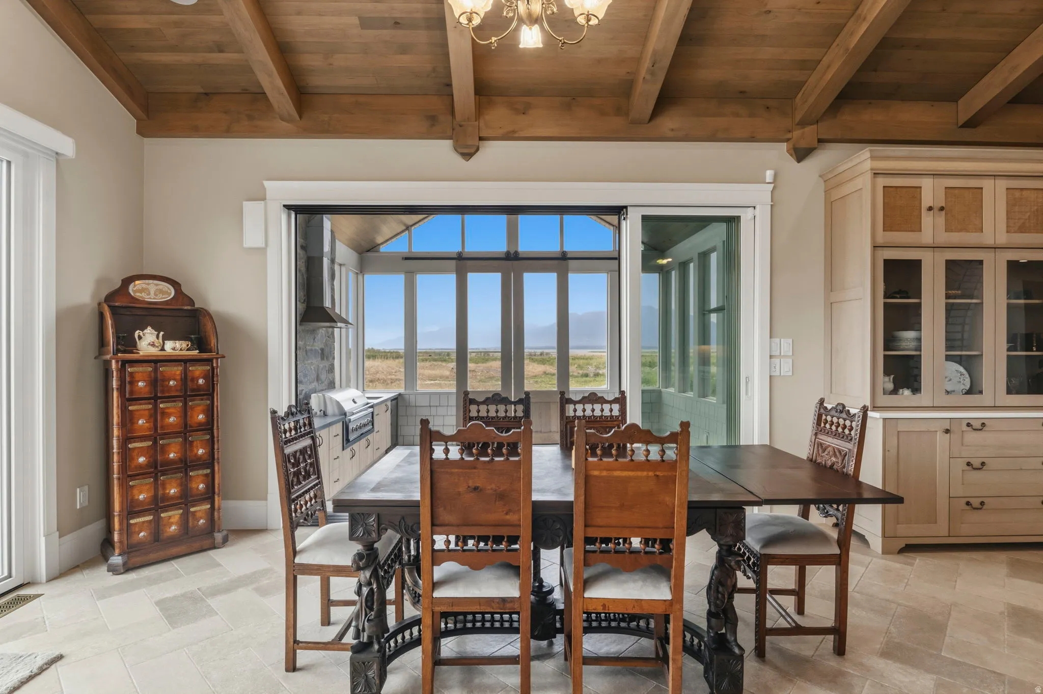 Dining area featuring a wood-finish beamed ceiling and tile flooring that invites you out to the outdoor kitchen.