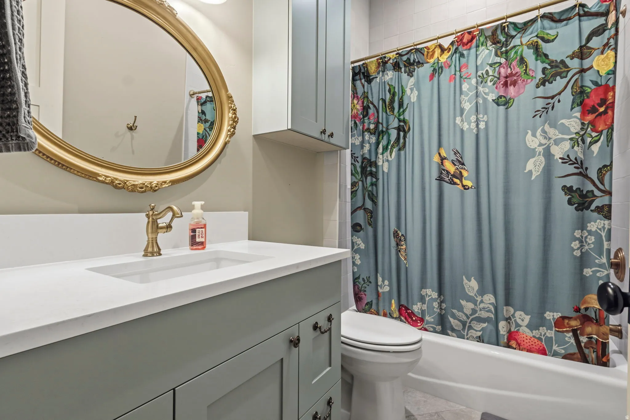 Bathroom featuring a light blue vanity with shaker-style cabinetry, a white countertop with integrated sink, and a brass-finish faucet
