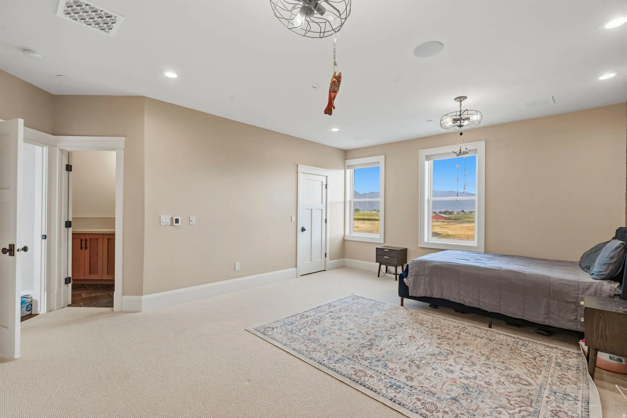 Spacious room featuring neutral paint tones, recessed lighting, and two windows offering expansive landscape views