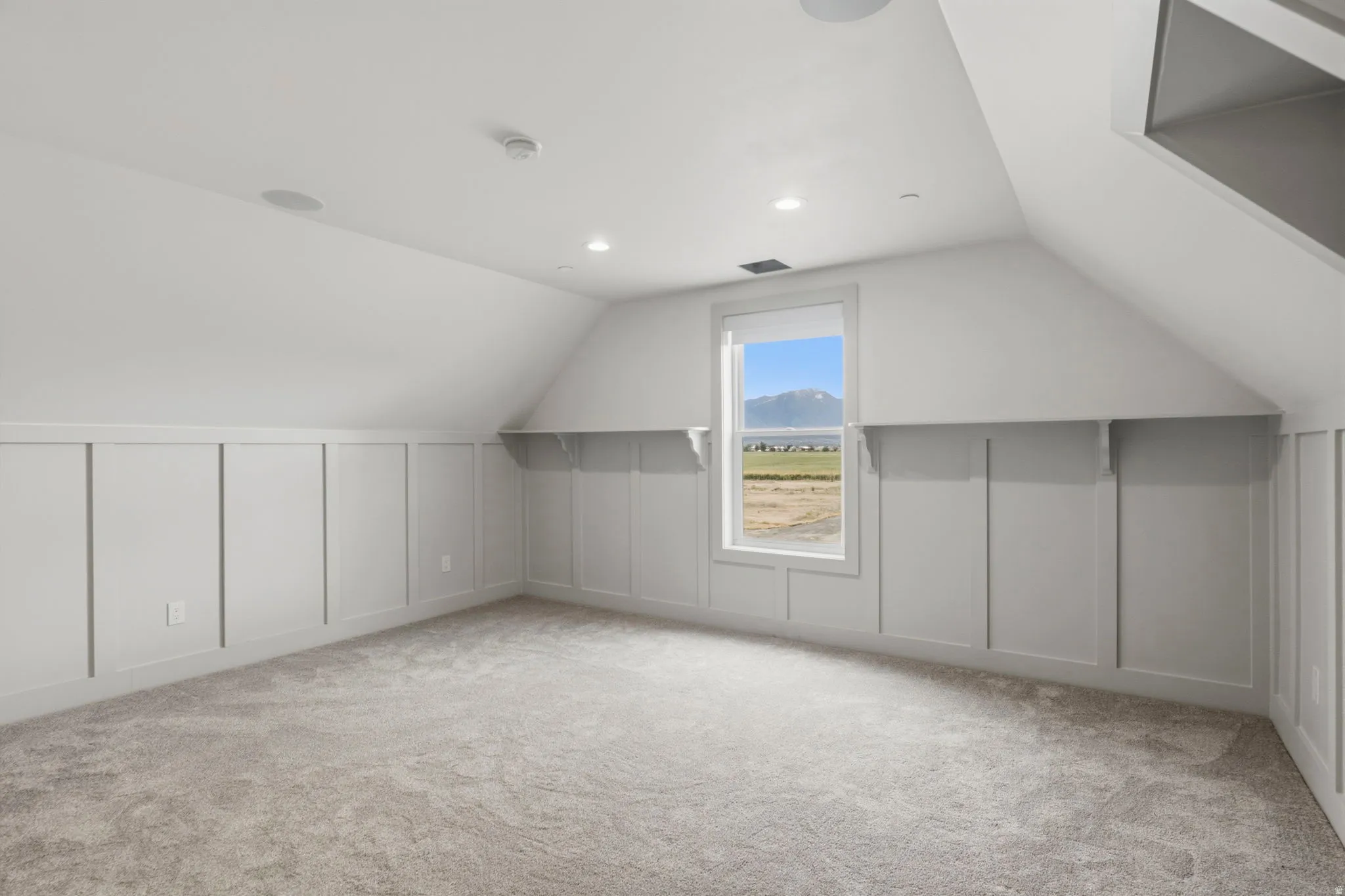 Quiet Interior room behind hidden door in attic space featuring sloped ceilings, recessed lighting, and a window with mountain scenery