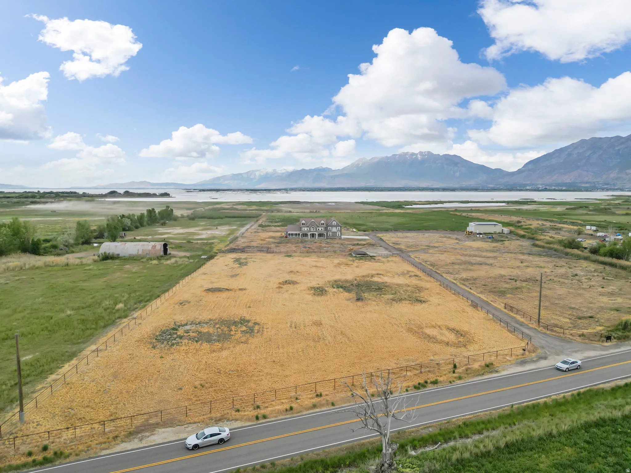 Expansive parcel featuring a large, undeveloped field, perimeter fencing, and a paved road frontage