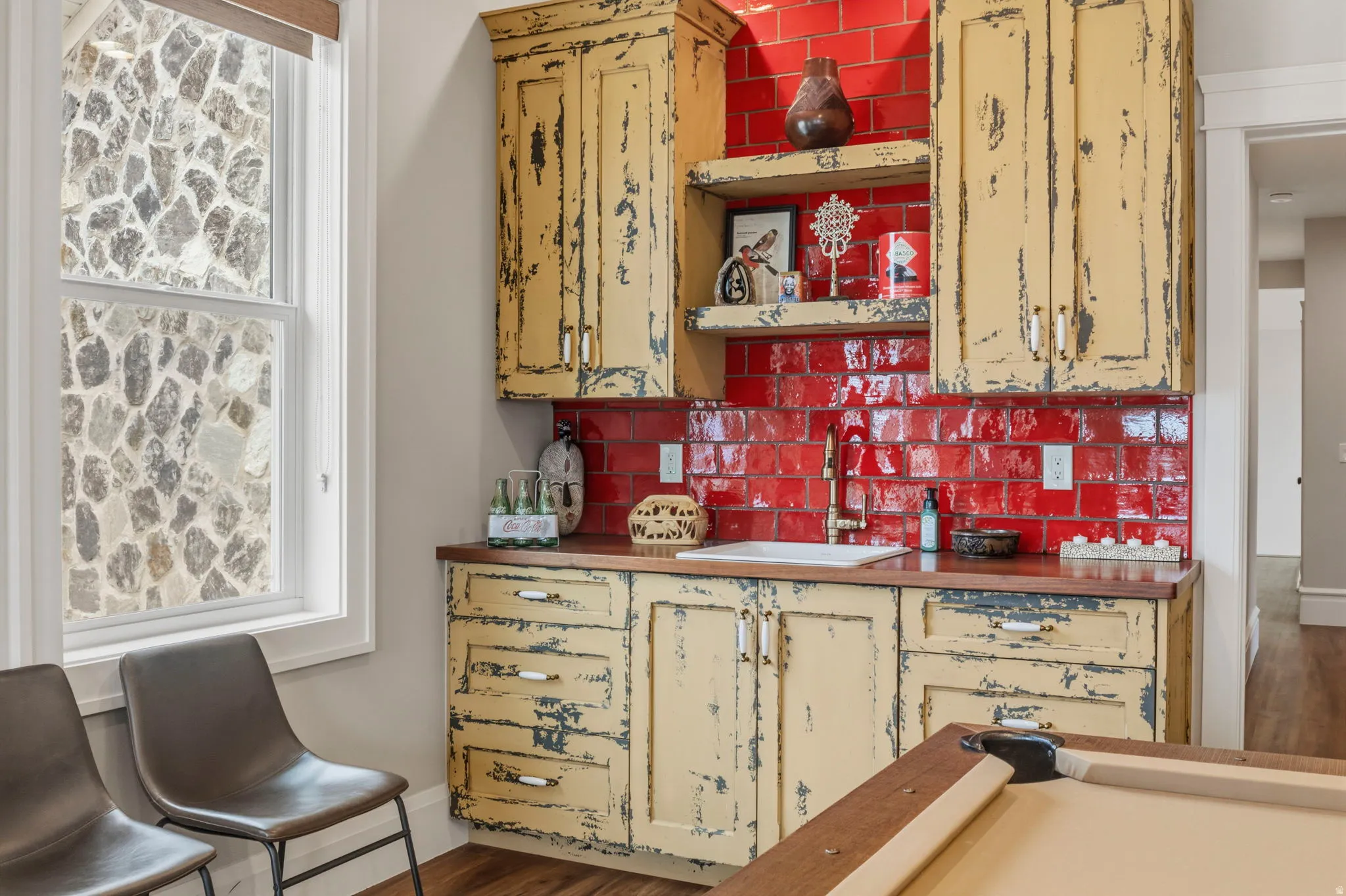 Wet bar featuring distressed cabinetry, a red subway tile backsplash, and a built-in sink with a gold-toned faucet