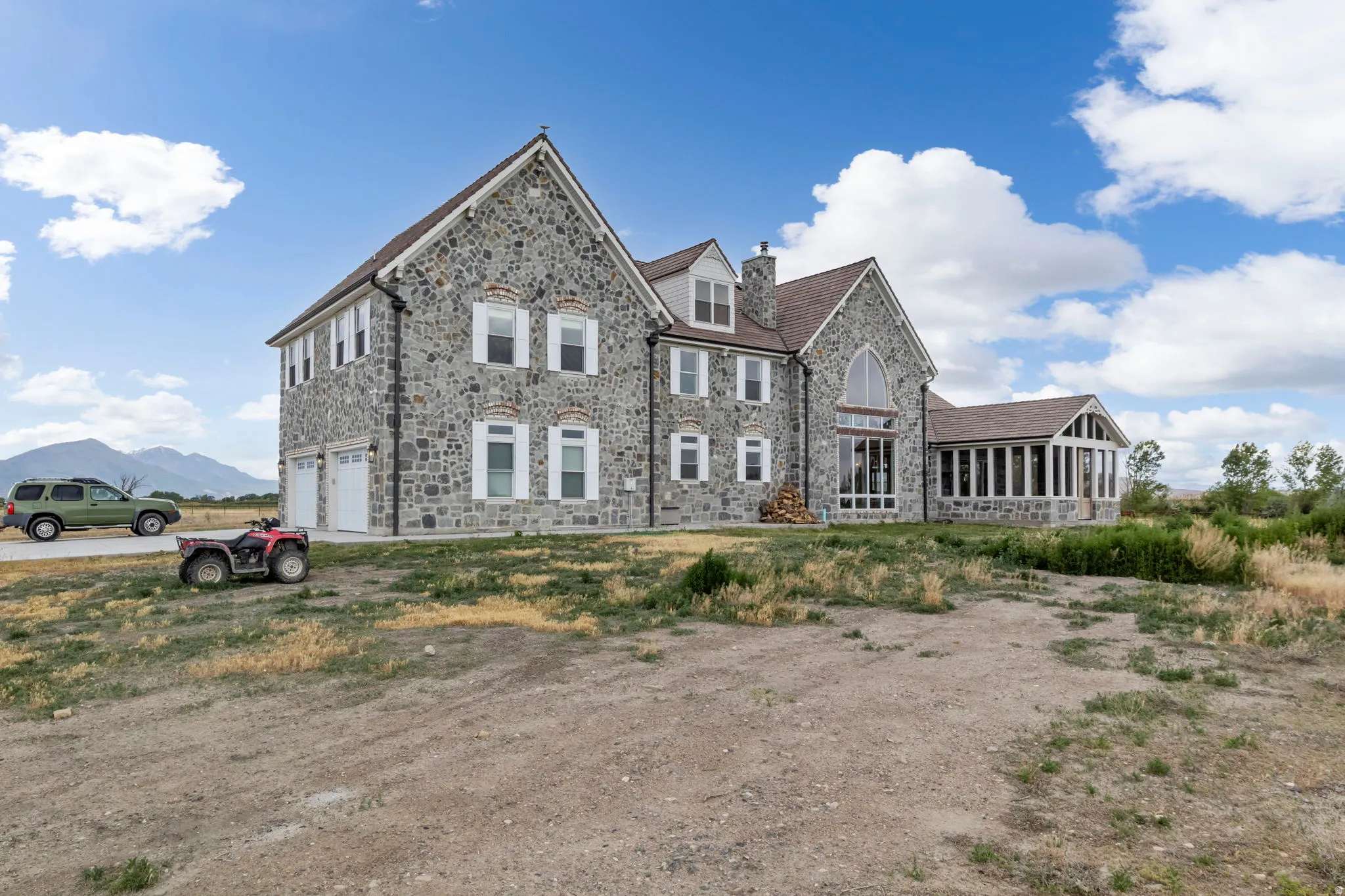 Stone exterior residence featuring a multi-gabled roofline and a pronounced arched window