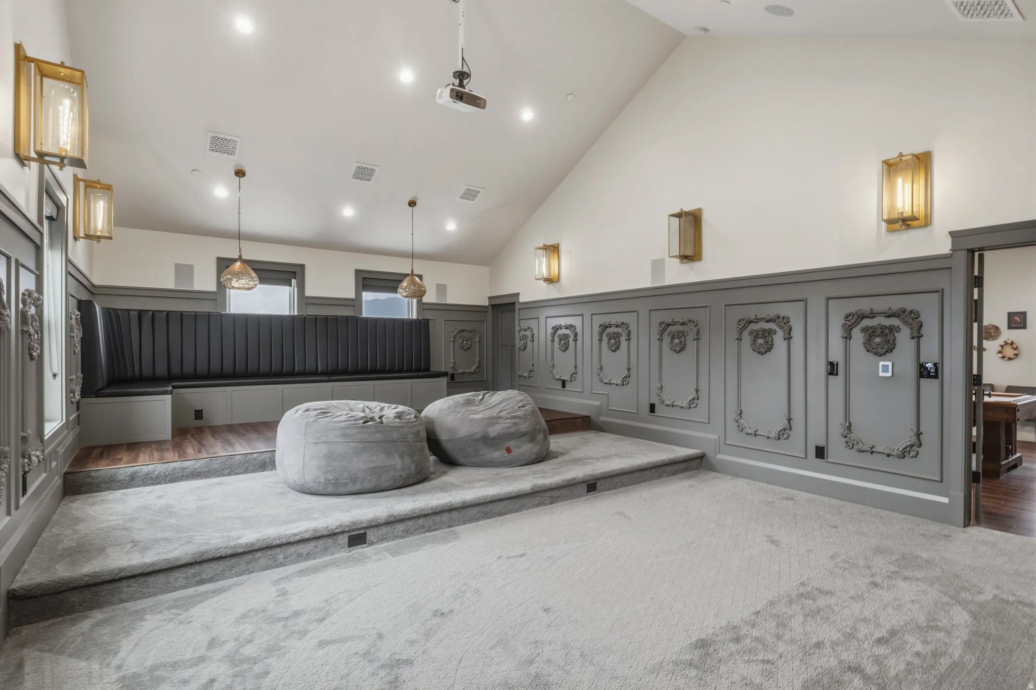 Theatrical room featuring tiered carpeted flooring and an elevated seating area with a built-in upholstered bench