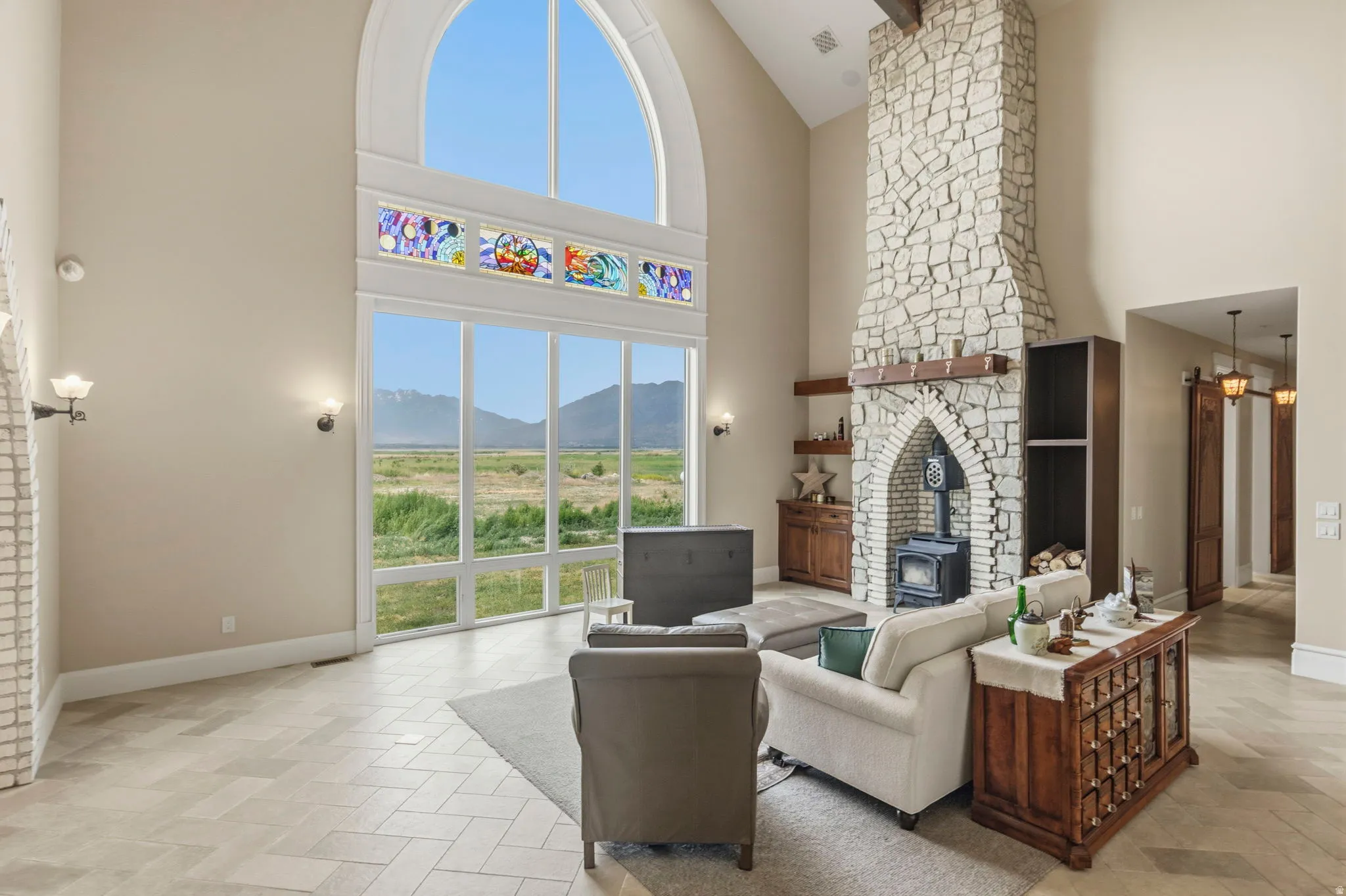Soaring vaulted ceilings with exposed beams complement the full-height stone fireplace featuring an arched hearth