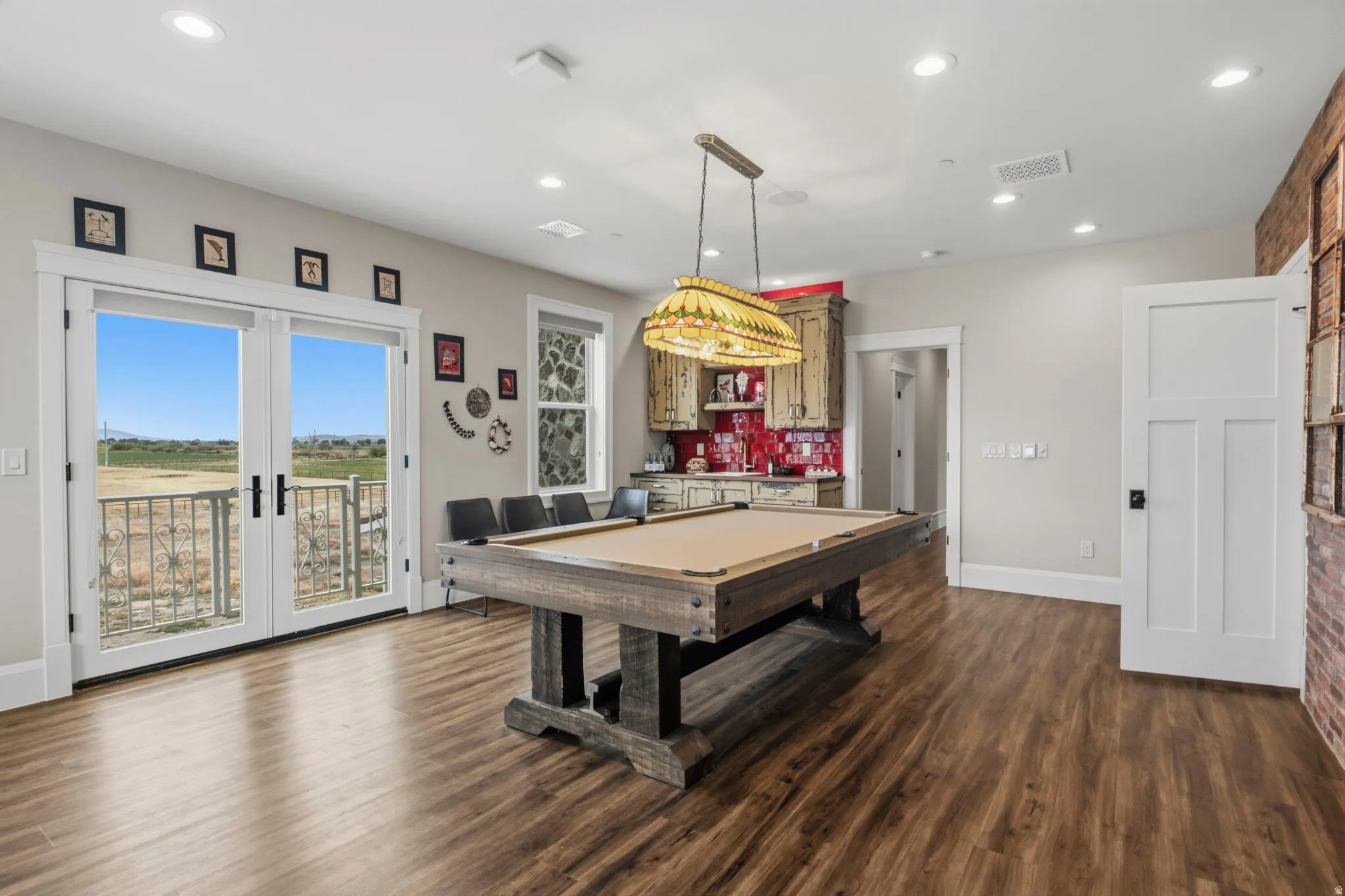 Spacious entertainment room featuring wood-finish flooring, a built-in wet bar with red tile backsplash, and recessed lighting