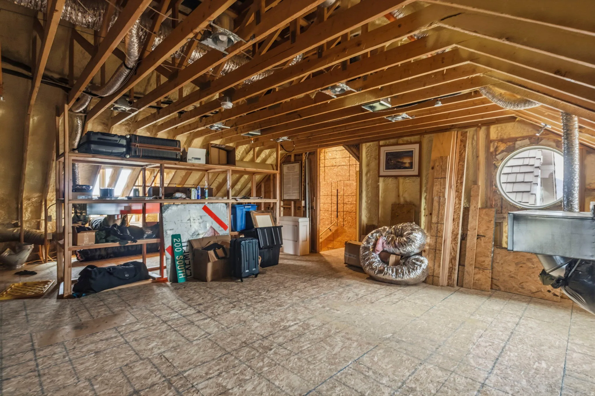 Attic space featuring exposed wood beam ceiling, unfinished wood flooring, and built-in wood shelving