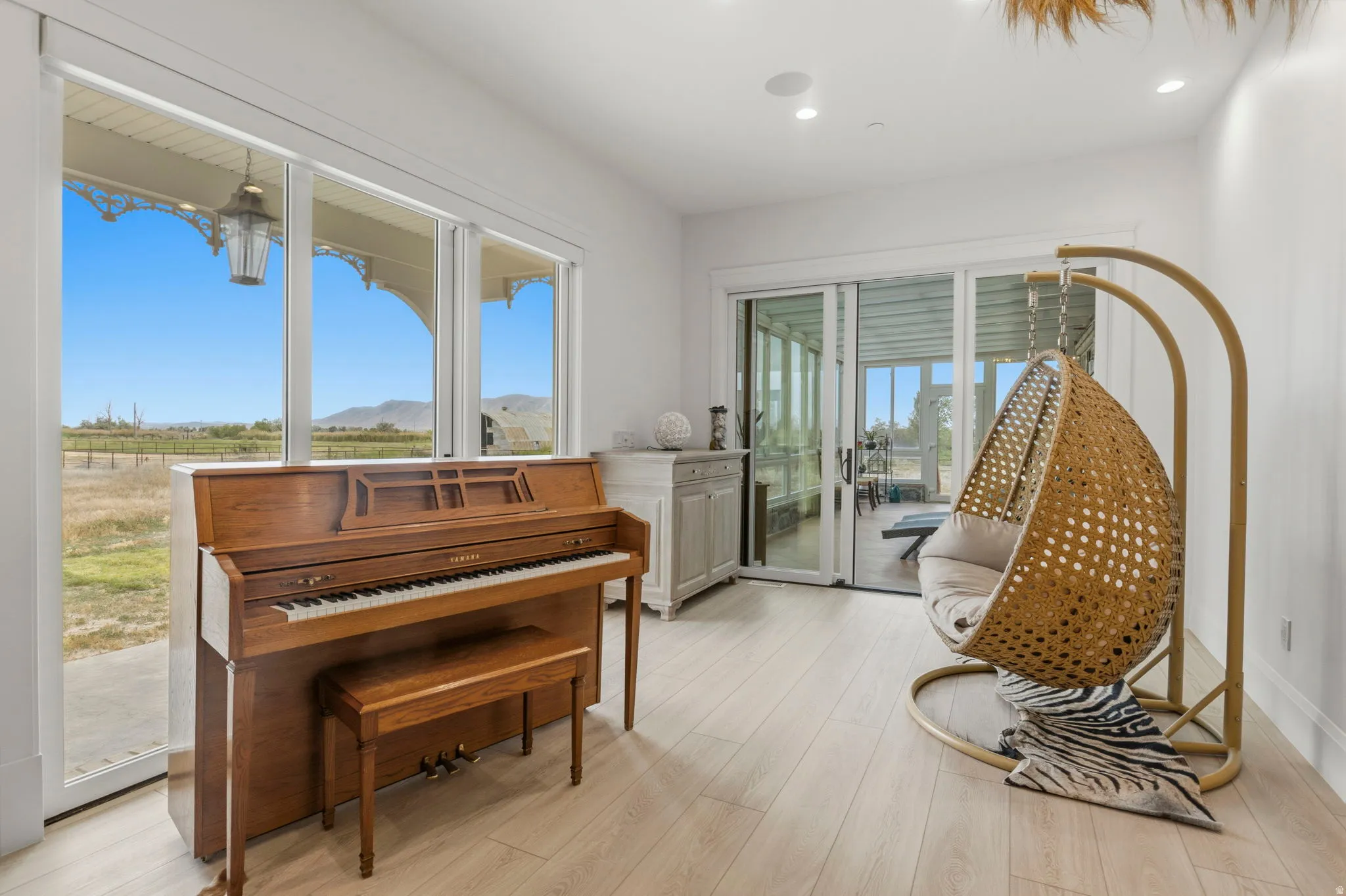 White walls and wood-finish flooring provide a neutral backdrop for floor-to-ceiling windows, offering expansive outdoor views from this serene Library.