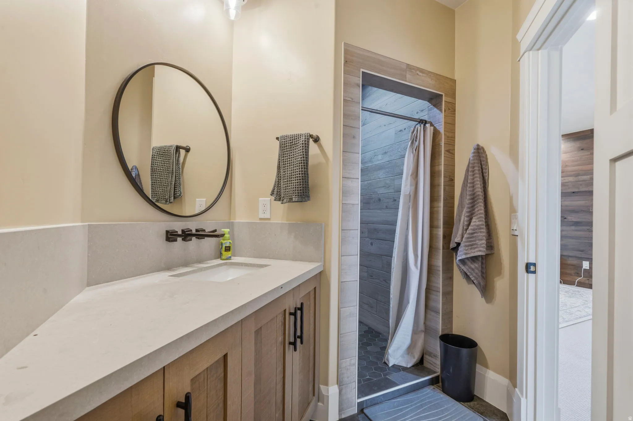 Bathroom vanity with a contemporary wall-mounted faucet, an integrated sink, and a circular mirror