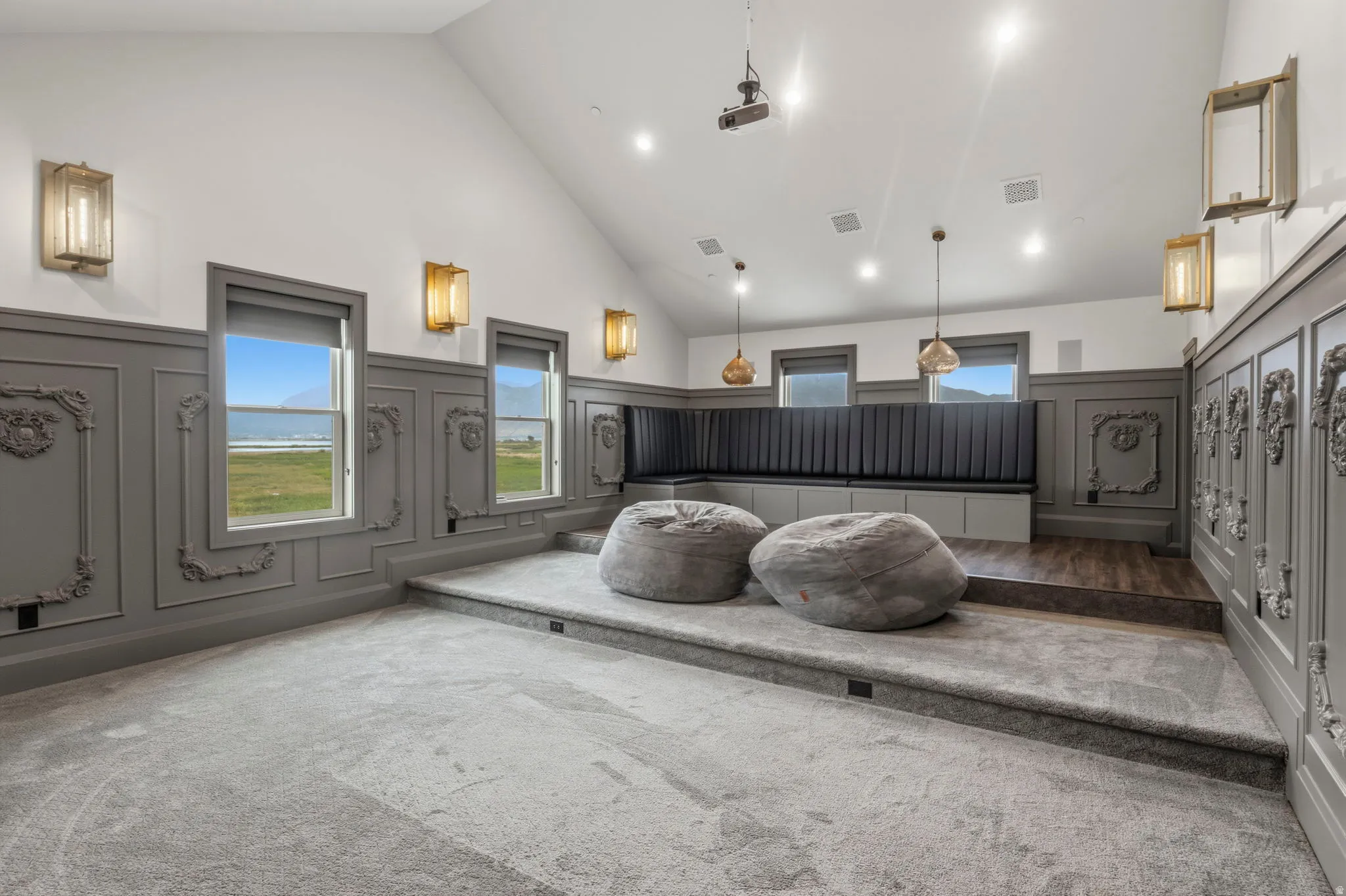 Theater room featuring tiered carpeted flooring, decorative wainscoting, recessed lighting, and a built-in bench seating area