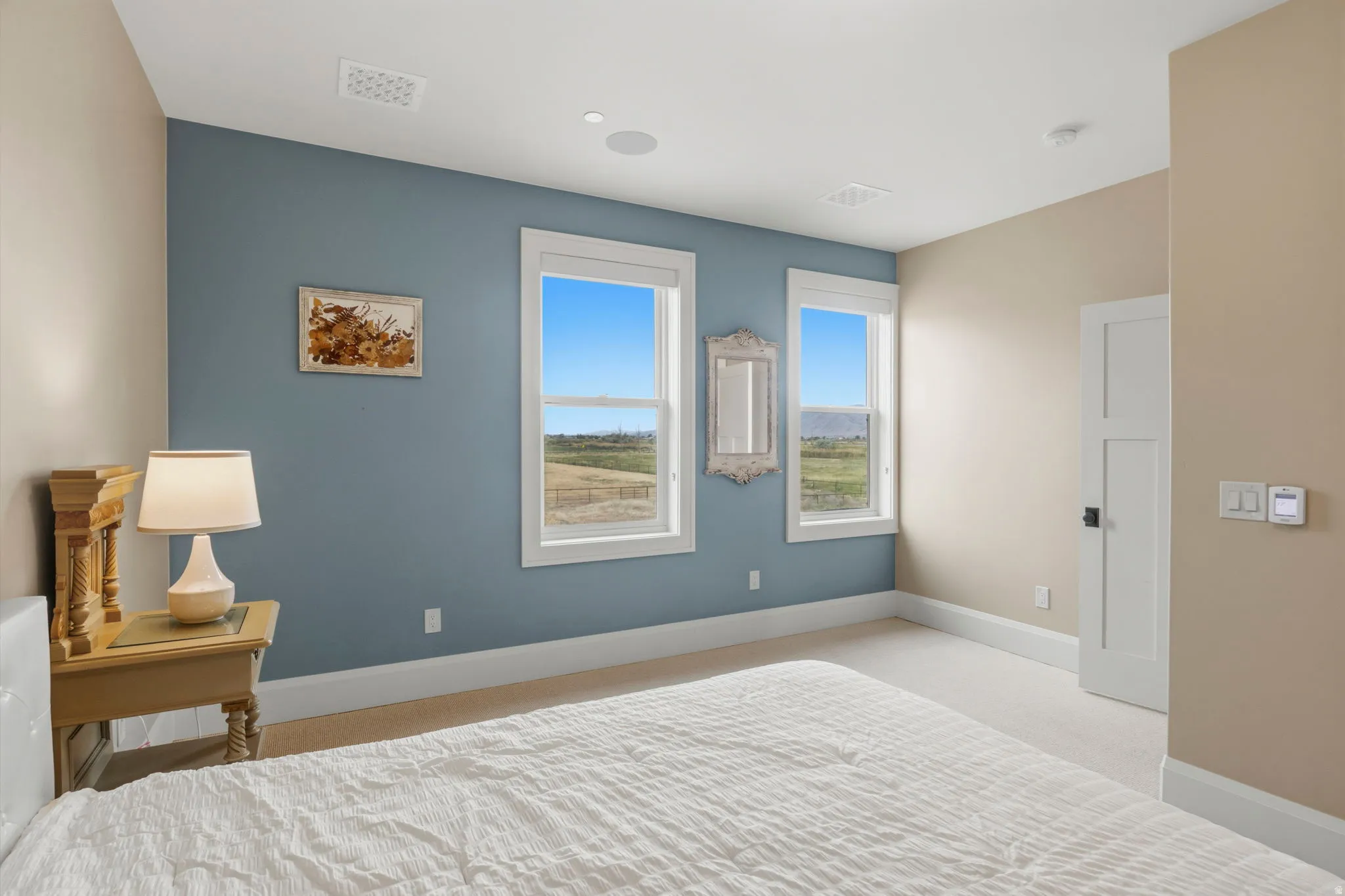 Room featuring two windows with white trim, a light blue accent wall, recessed lighting, and light-colored carpeting