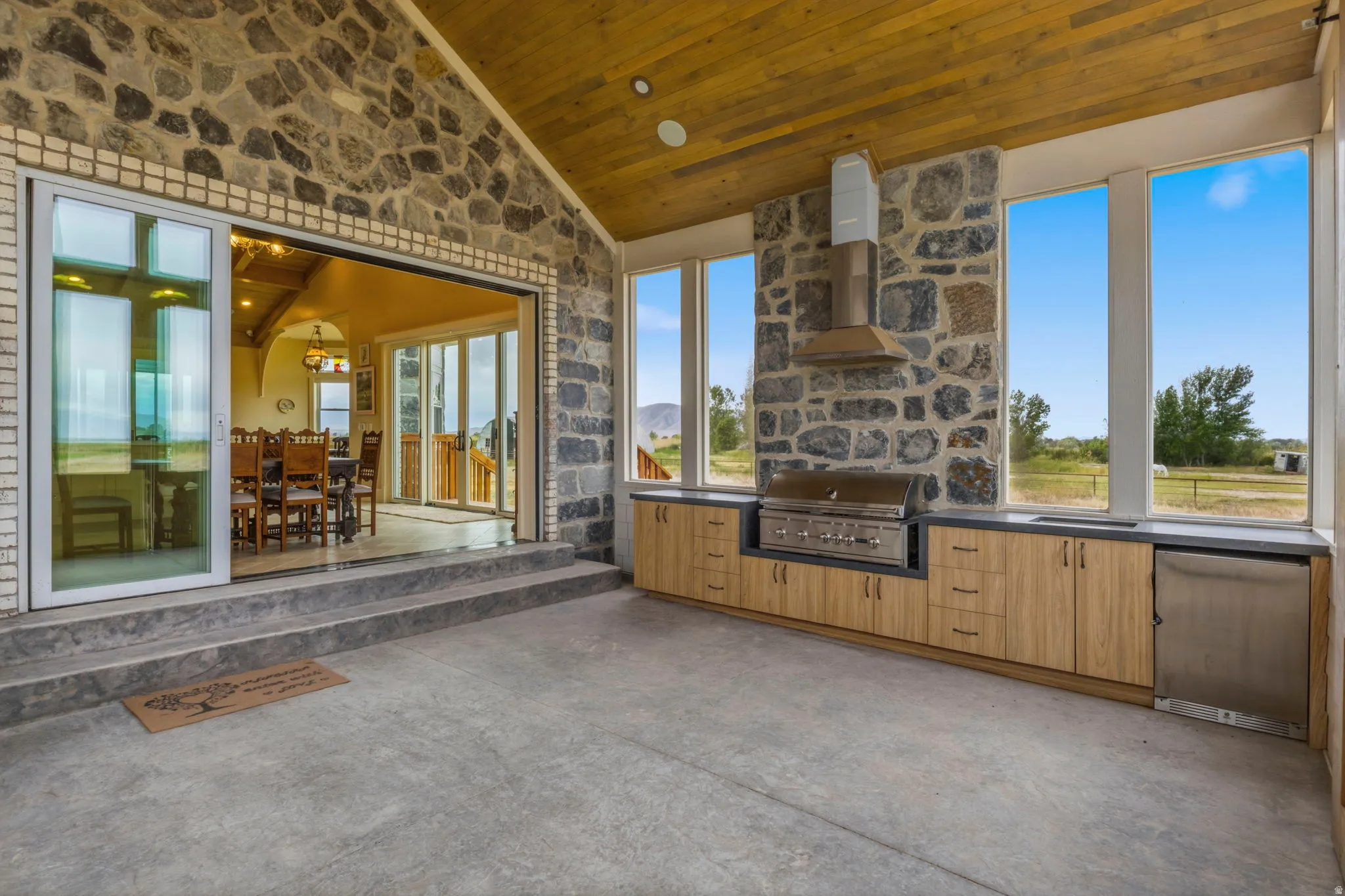 Expansive outdoor kitchen featuring an outdoor kitchen with an integrated grill, stainless steel hood, and built-in dishwasher