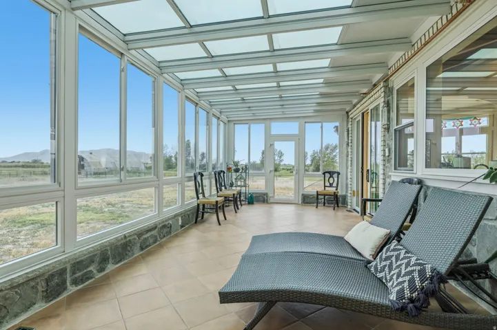 Solarium Sunroom featuring a full glass roof, floor-to-ceiling windows, stone base, tile flooring, and exterior access for enjoying nature in style.