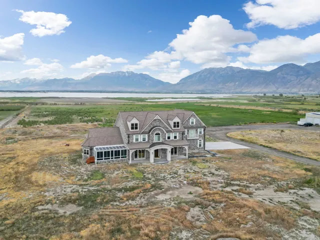 Stone facade residence featuring a covered entry porch, multiple gables, a sunroom with extensive windows, and a paved driveway leading to the property