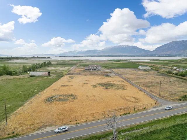 Expansive parcel featuring a large, undeveloped field, perimeter fencing, and a paved road frontage
