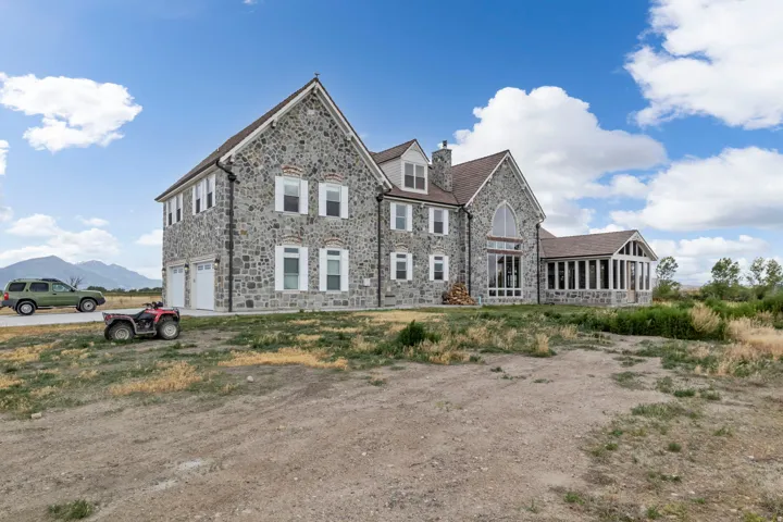 Stone exterior residence featuring a multi-gabled roofline and a pronounced arched window