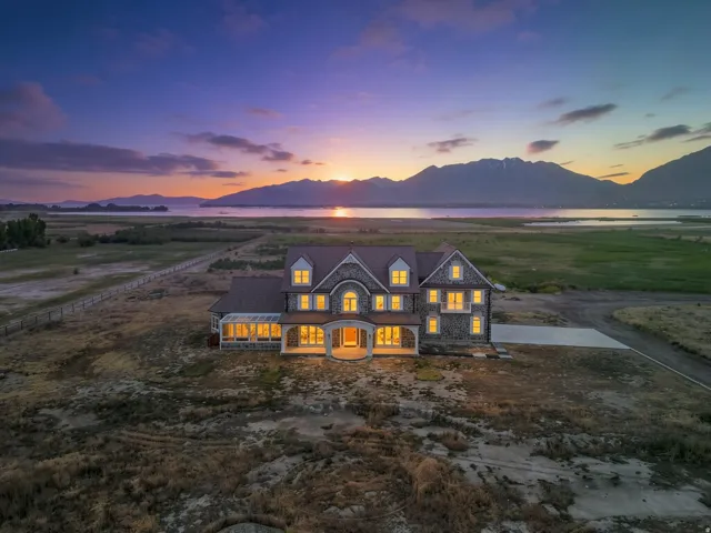 Stone-clad estate with multiple dormers, a covered front porch, and an attached sunroom. Backs up to Utah Lake.