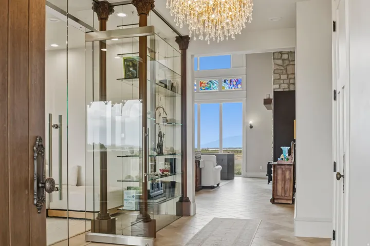 Grand entryway featuring a large crystal chandelier, tile flooring, and a glass-enclosed library