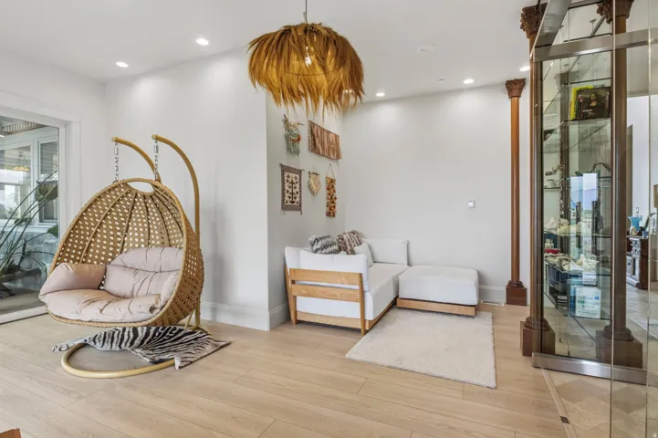 Light wood-finish flooring with recessed ceiling lighting, a decorative pendant light fixture, and a built-in display case with glass shelving. Peaceful Library with ample natural light.