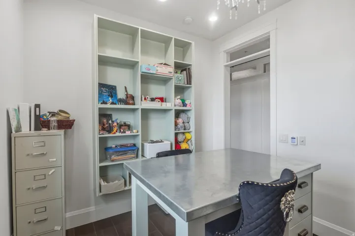 Integrated shelving unit with multiple compartments, a built-in countertop work surface, recessed lighting, and dark wood-finish flooring. This room doubles as an office and craft room.