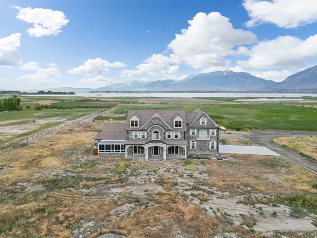 Grand stone and shingle-sided residence showcasing multiple dormers, an enclosed sunroom, and a prominent arched entryway