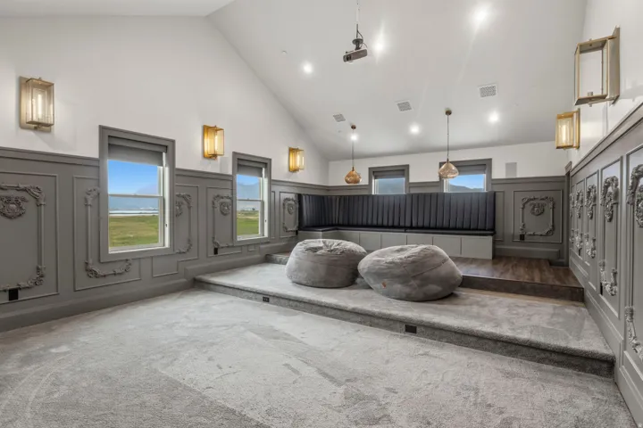 Theater room featuring tiered carpeted flooring, decorative wainscoting, recessed lighting, and a built-in bench seating area