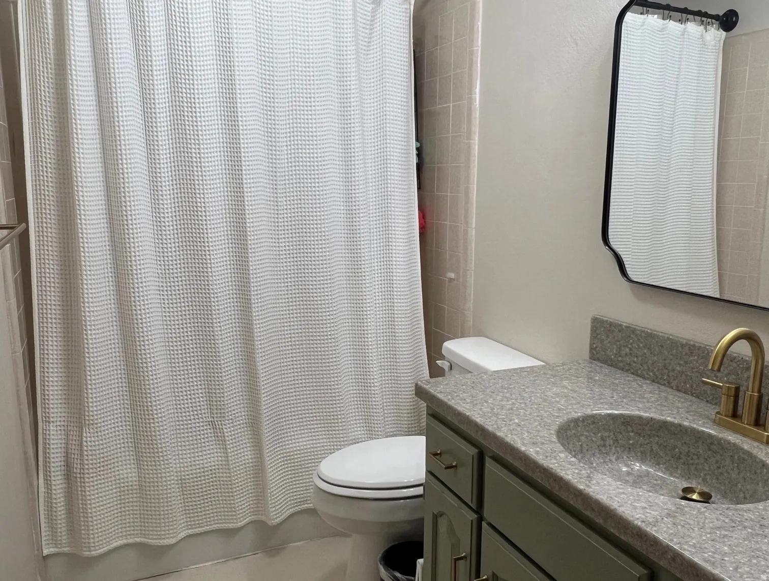 Bathroom featuring a vanity with a mottled countertop, an integrated sink, and an antique brass-finish faucet