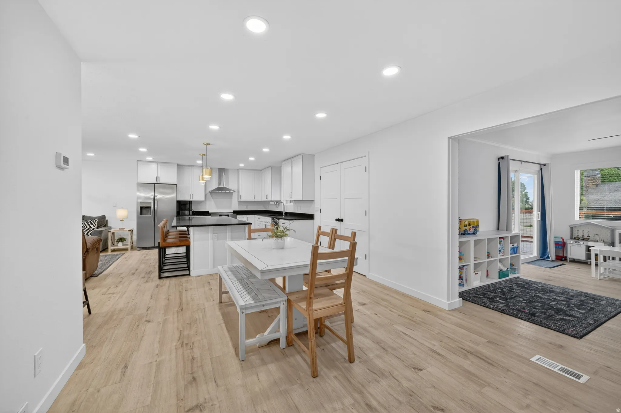 Open-concept living space featuring LVP flooring, recessed lighting, and a white kitchen with dark countertops