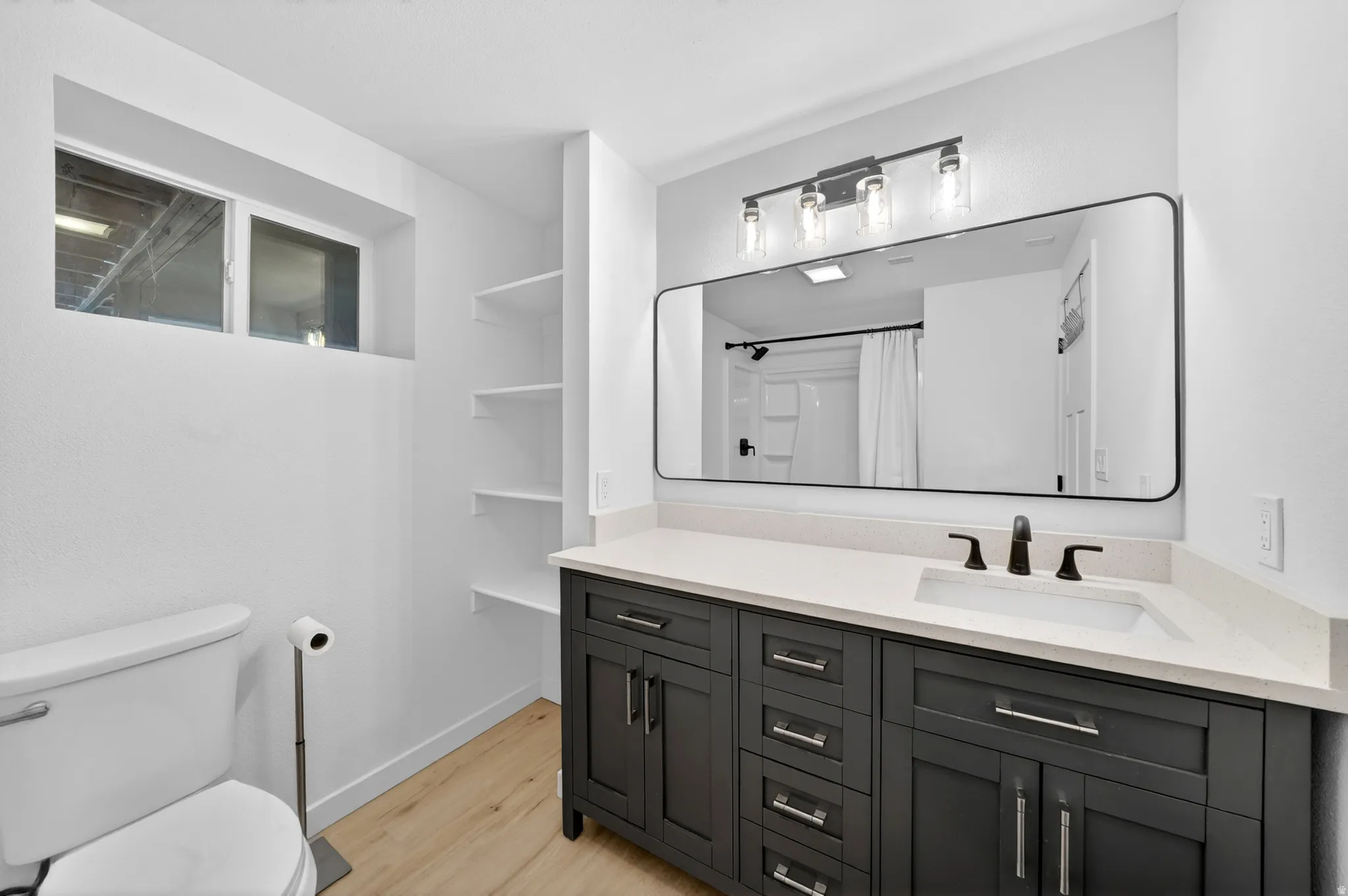 Bathroom featuring a dark wood-finish vanity with a light countertop, a rectangular undermount sink, and matte black fixtures