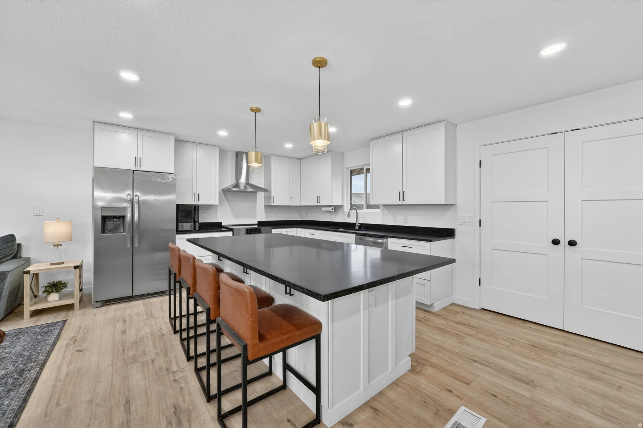 Modern kitchen featuring a large central island with seating, white shaker cabinetry, stainless steel appliances, and LVP flooring