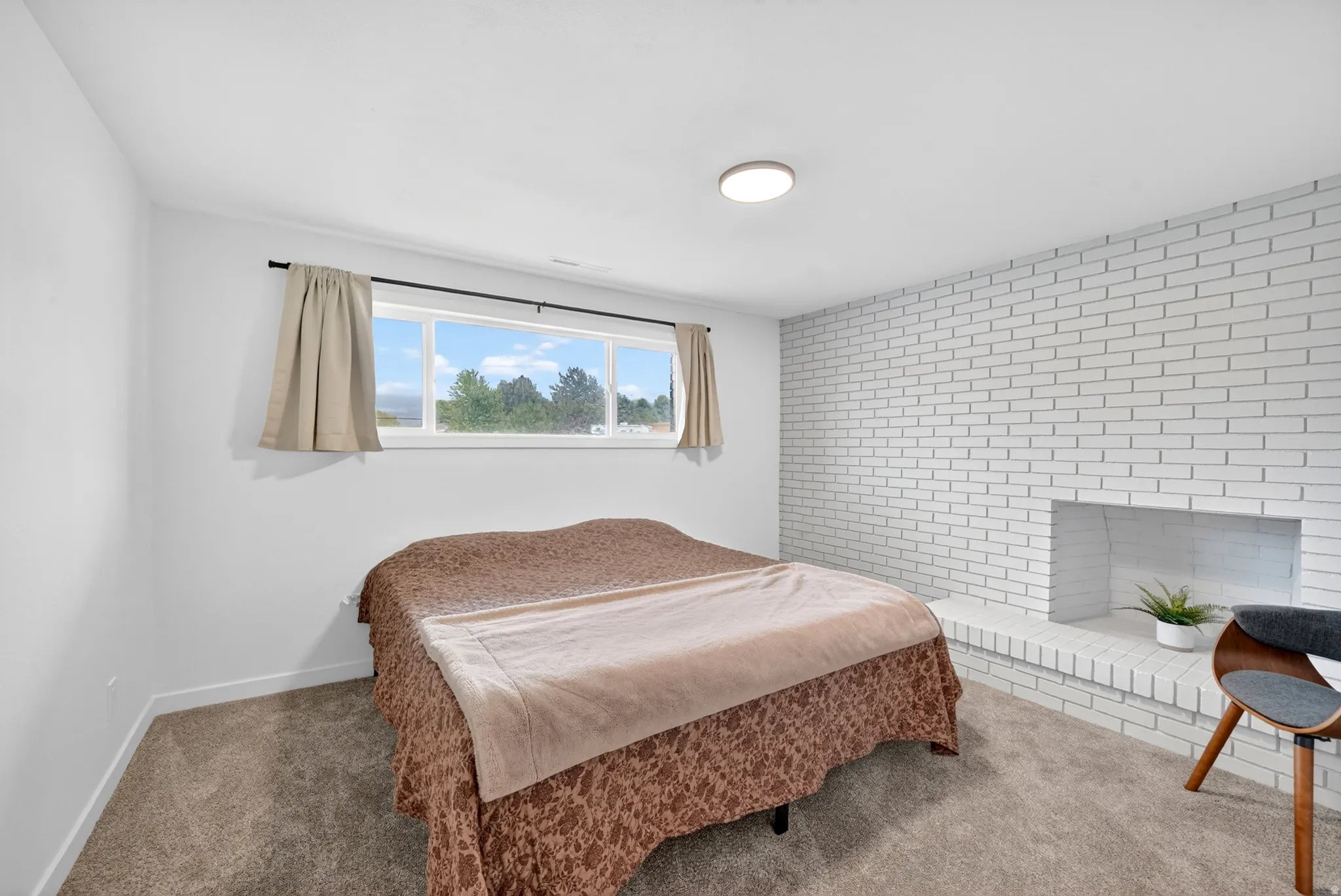 Room featuring white painted brick accent wall with a built-in fireplace hearth