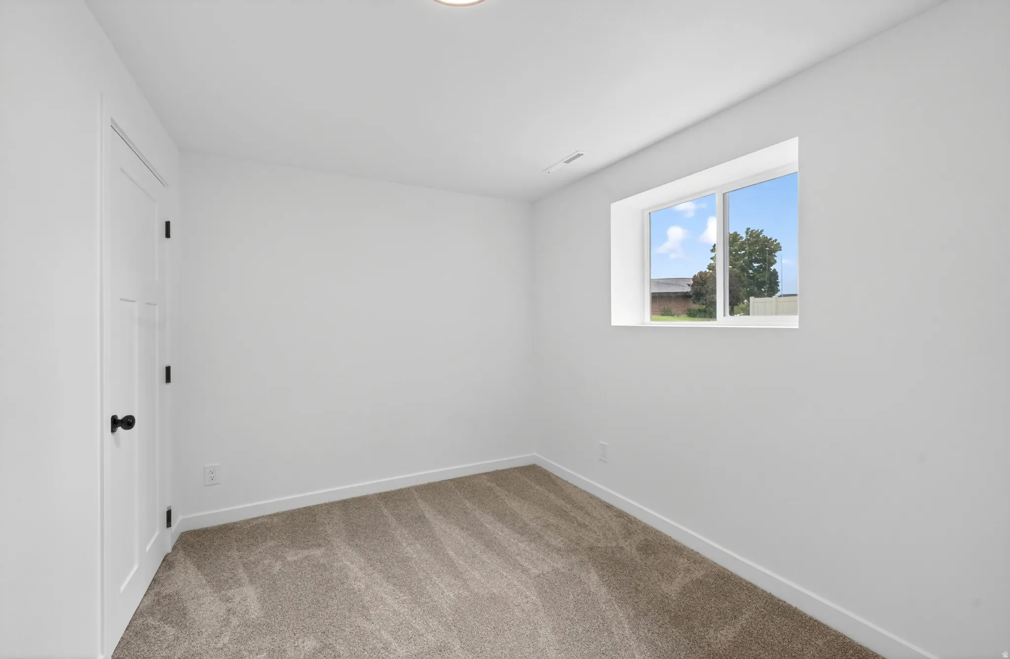 Carpeted room featuring a white interior door with dark hardware, a rectangular window, recessed lighting, and white baseboards