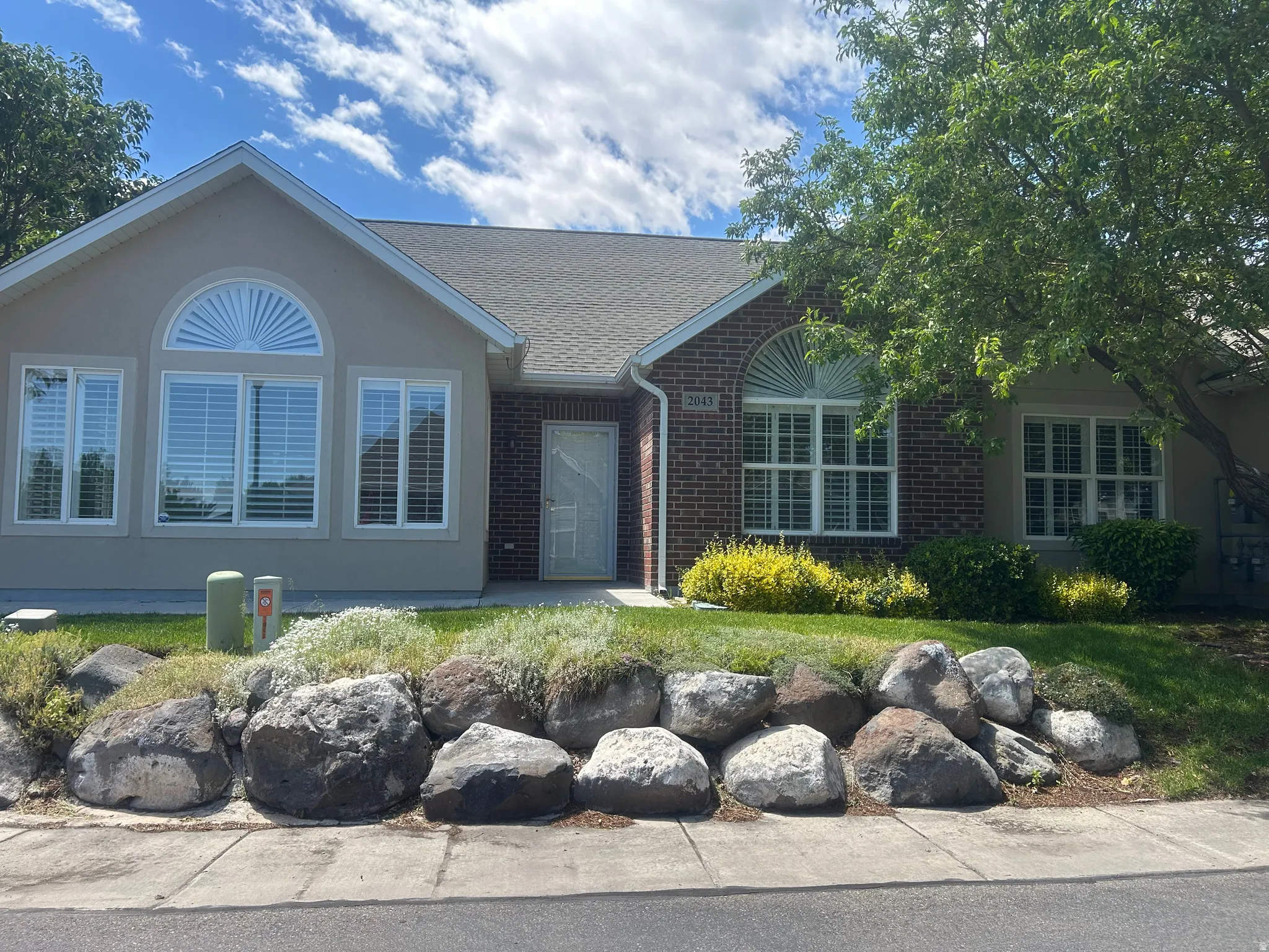 Exterior facade featuring a stucco and brick combination, arched window accents, and white window shutters