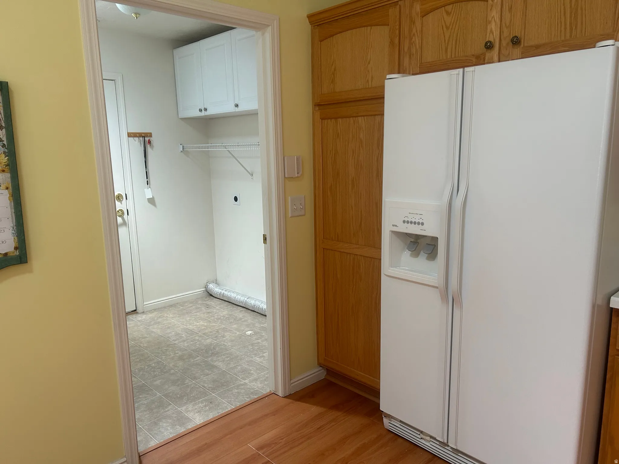 Dedicated utility room with white cabinetry and wire shelving, complemented by wood-finish flooring