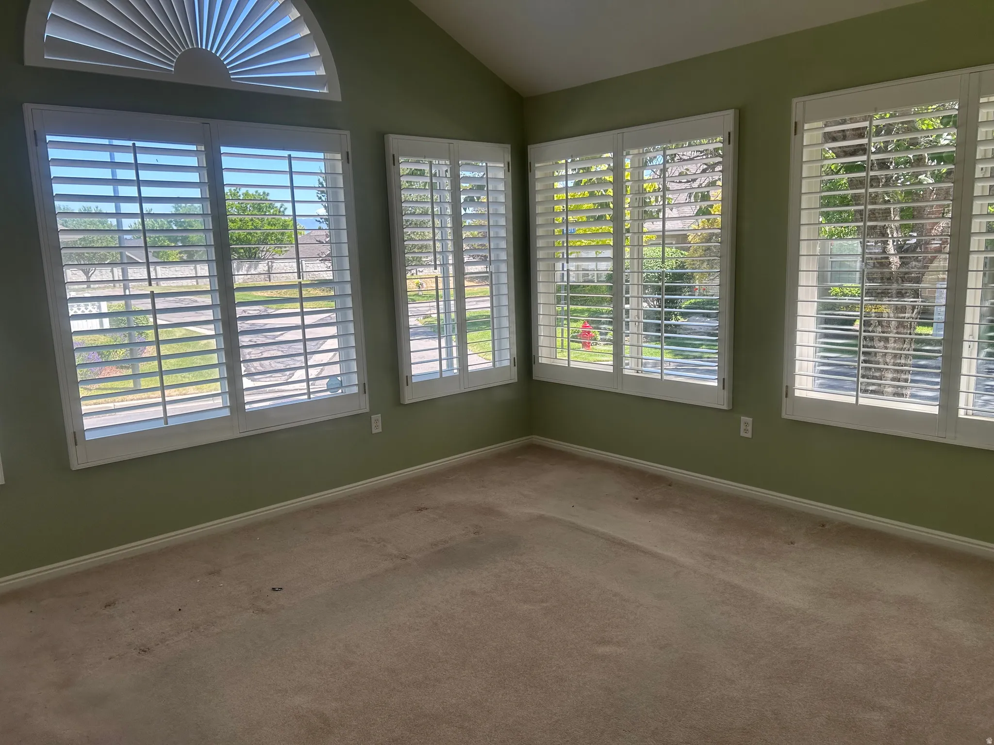 Interior space featuring a vaulted ceiling and an arched window with louvered shutters